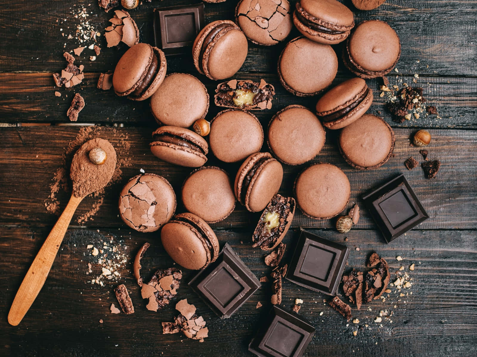 Brown Chocolate 桌布 壁紙 — 濃郁的巧克力馬卡龍和碎黑巧克力條散落在質樸的深色木質表面上，配以可可粉和榛子。