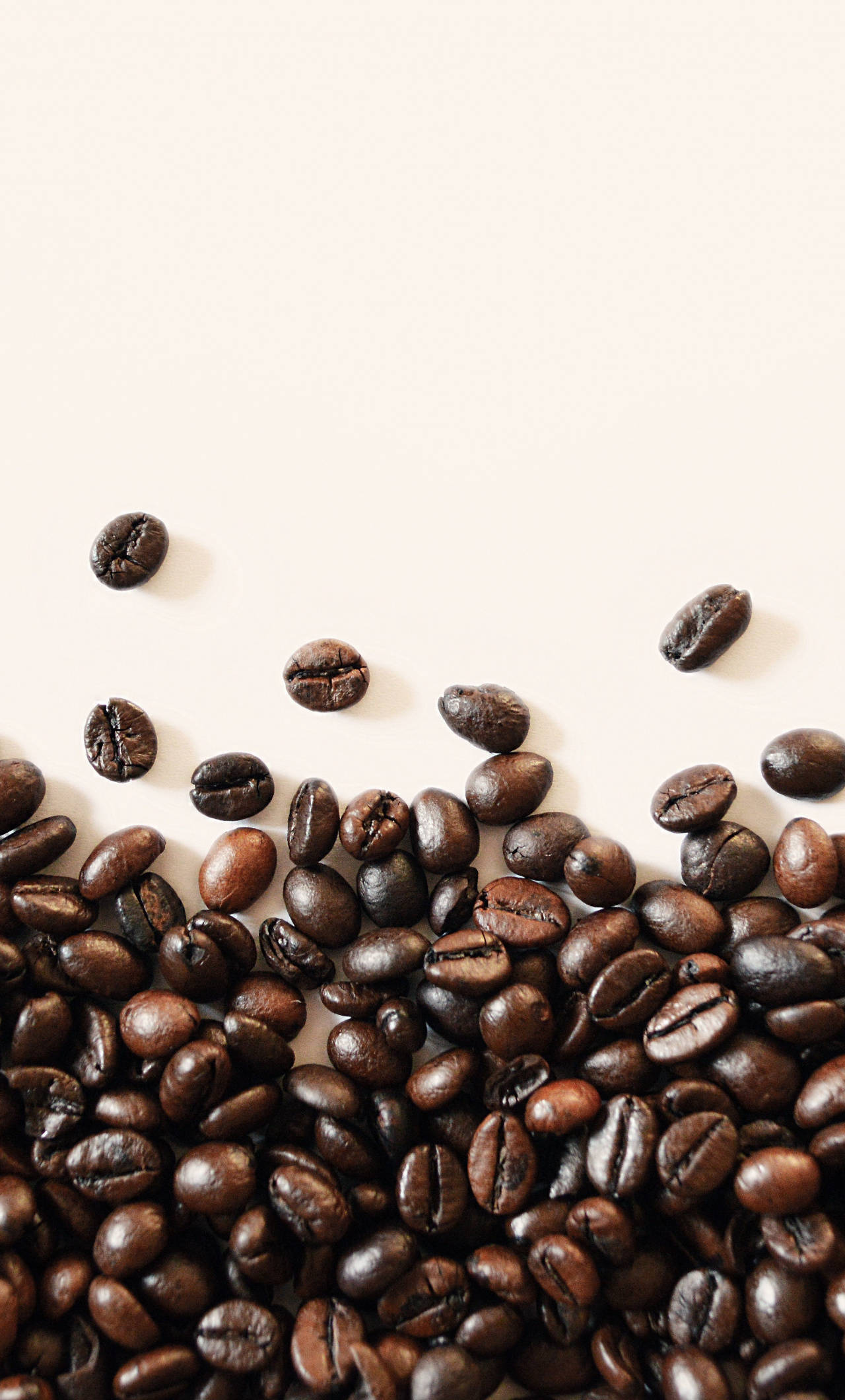 beans 桌布 壁紙 — 濃郁的深焙咖啡豆在極簡的米白色表面上形成紋理豐富的瀑布狀散落。