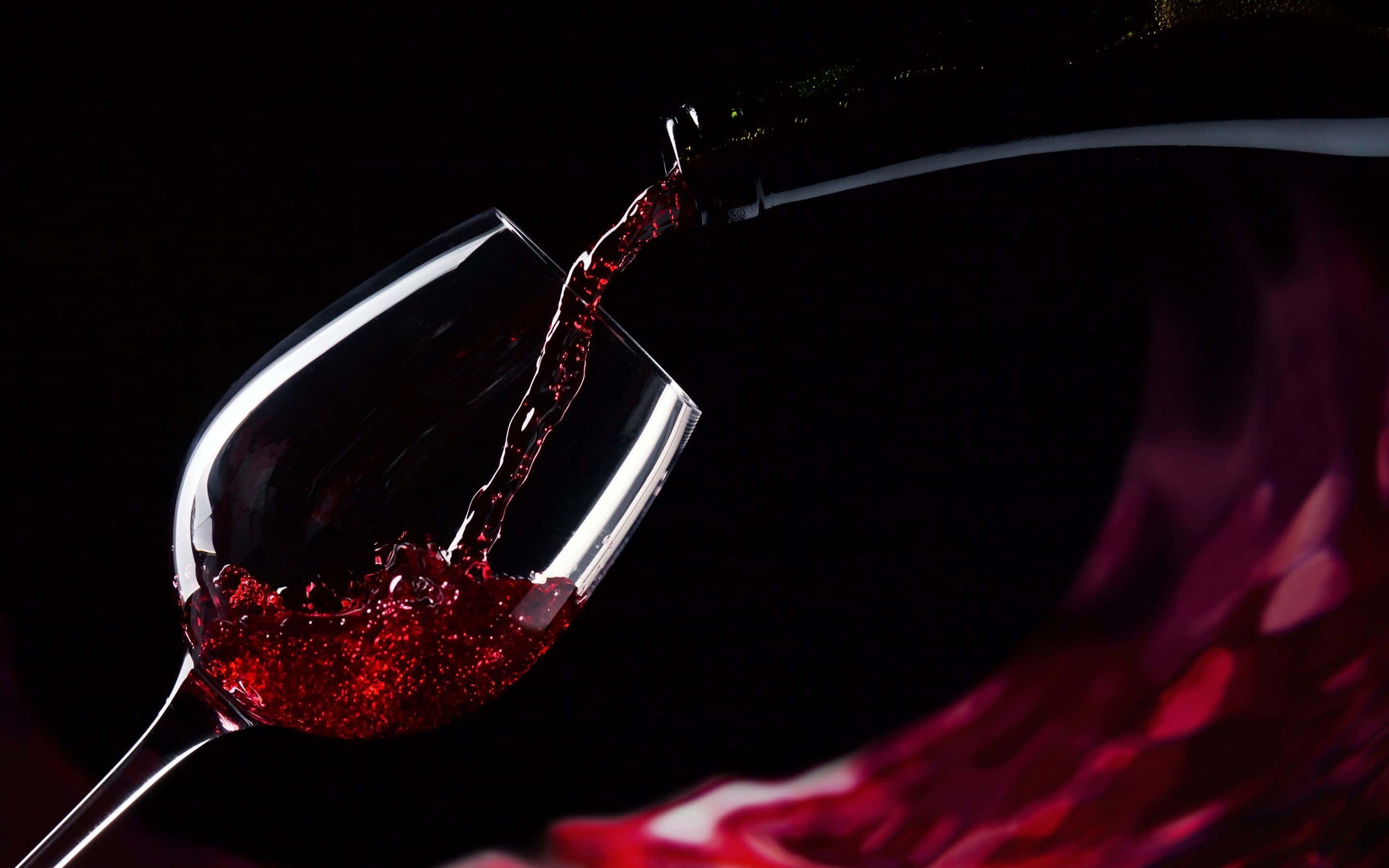 Red Wine Glass 桌布 壁紙 — 濃郁的紅酒動態地倒入水晶杯中，背景是純黑色，帶有發光的高光。