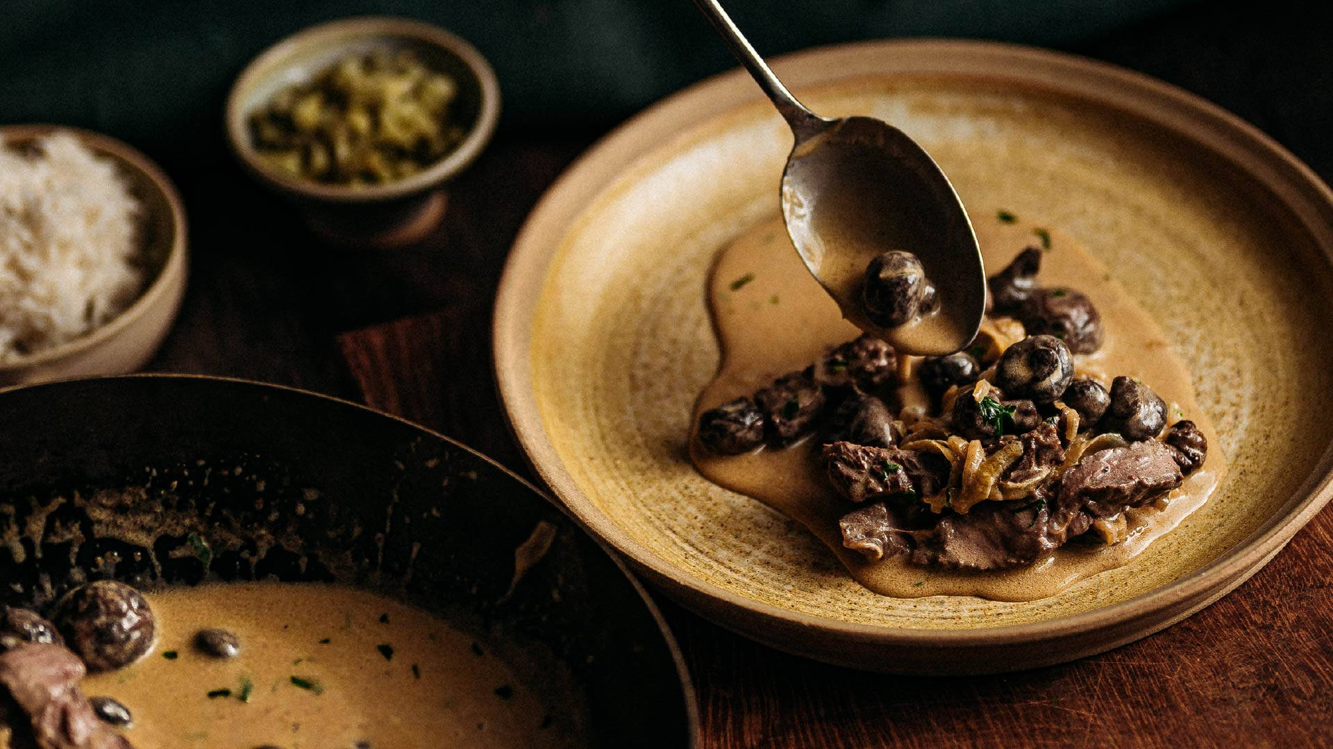 Food Photography 桌布 壁紙 — 濃郁的蘑菇肉醬正被舀到一個鄉村風格的盤子上，旁邊有米飯和醃菜。