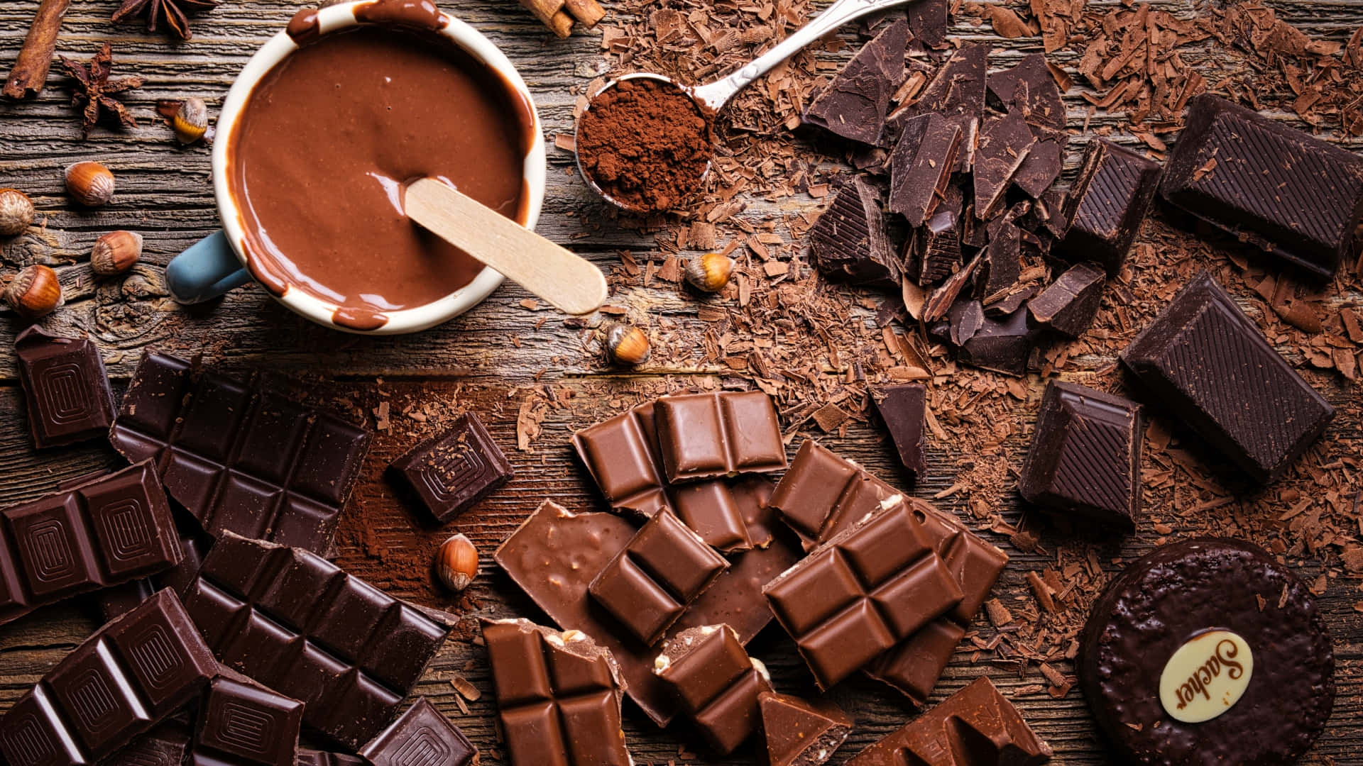 Dark Chocolate 桌布 壁紙 — 濃郁的黑巧克力條、可可粉和榛子散落在鄉村風格的木桌上。