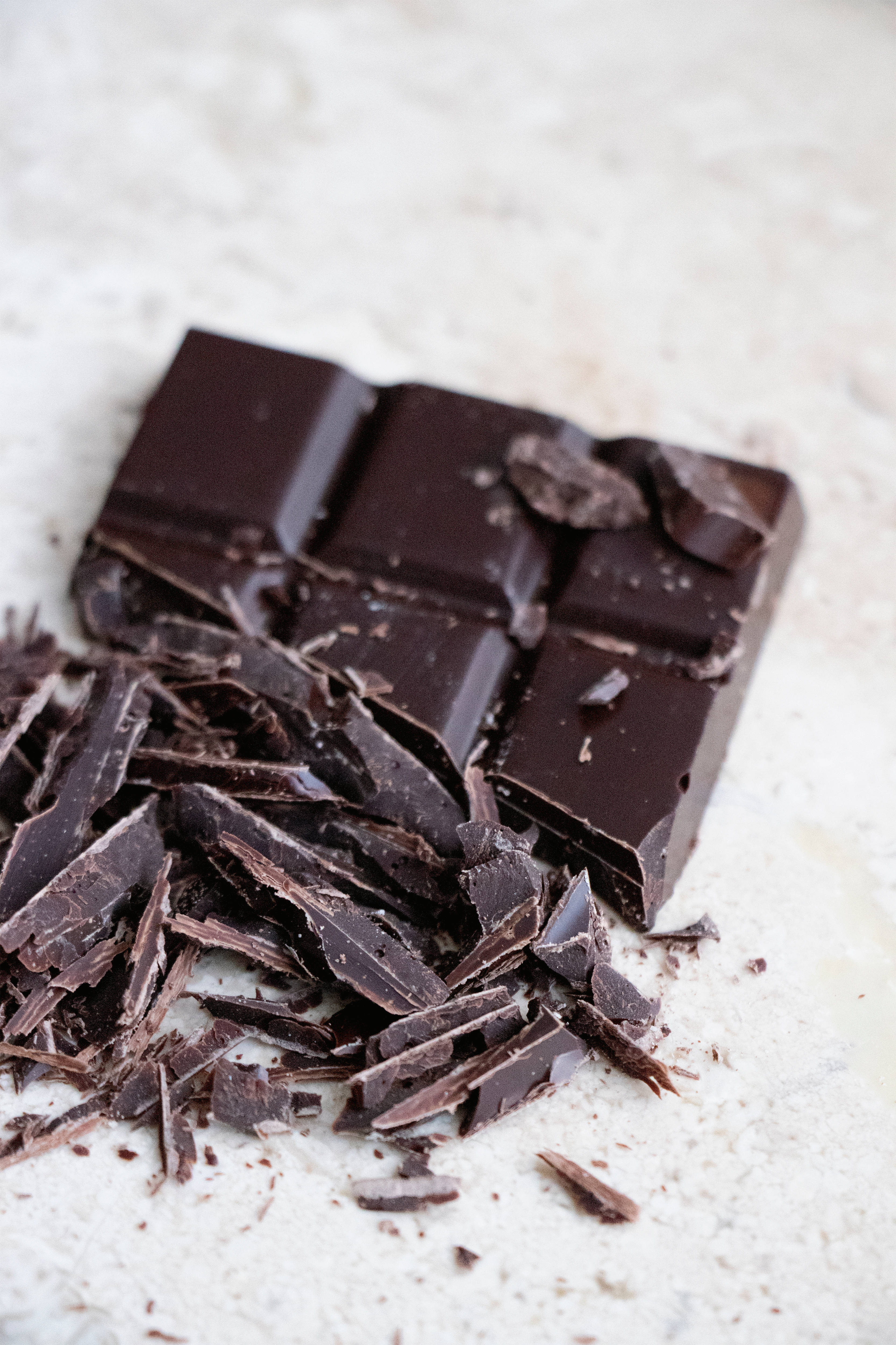 Chocolate 桌布 壁紙 — 濃郁的黑巧克力棒，碎塊散落在淺色紋理表面上。