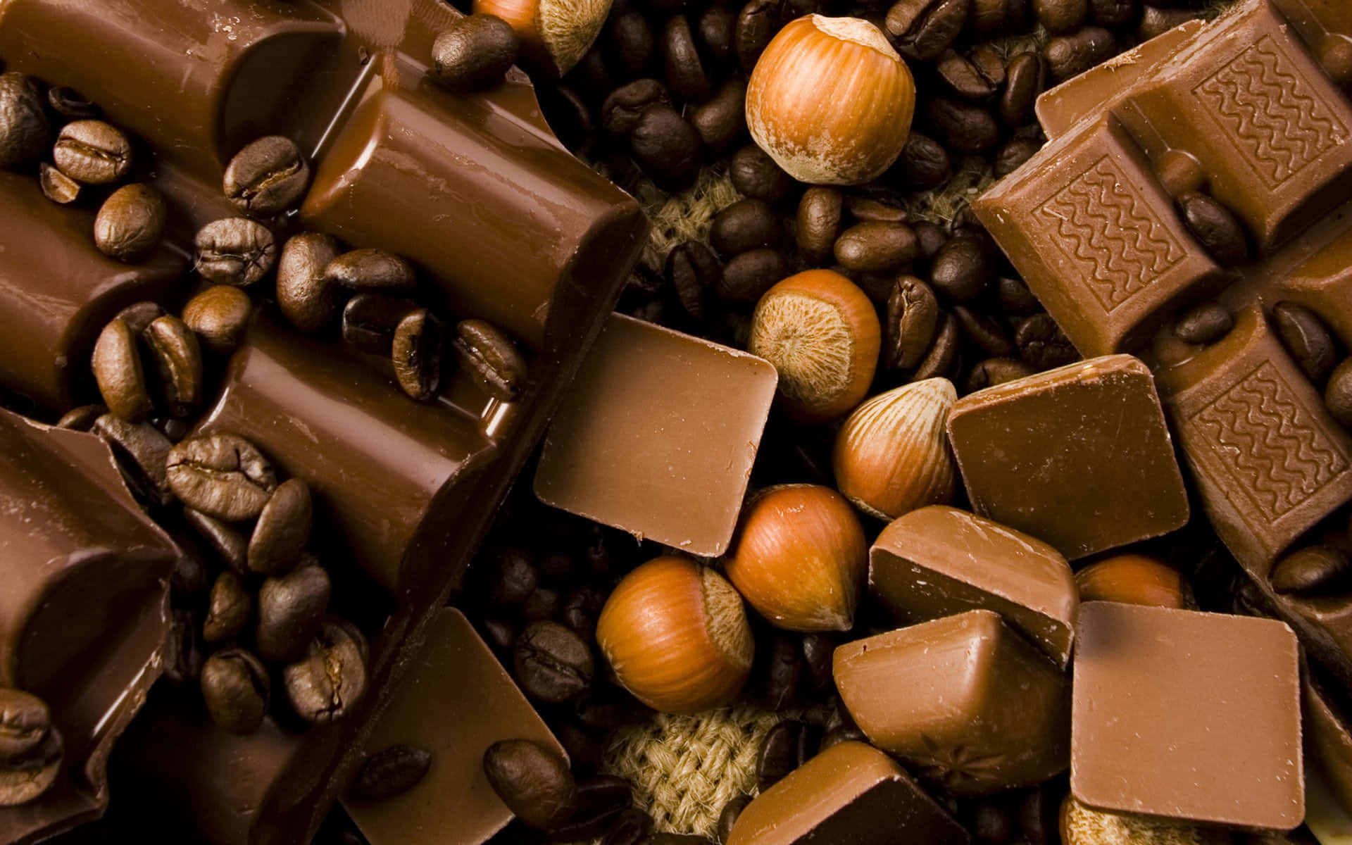 Brown Chocolate 桌布 壁紙 — 濃郁的黑巧克力棒和榛子藏在烤咖啡豆之間，呈現出頹廢的特寫。