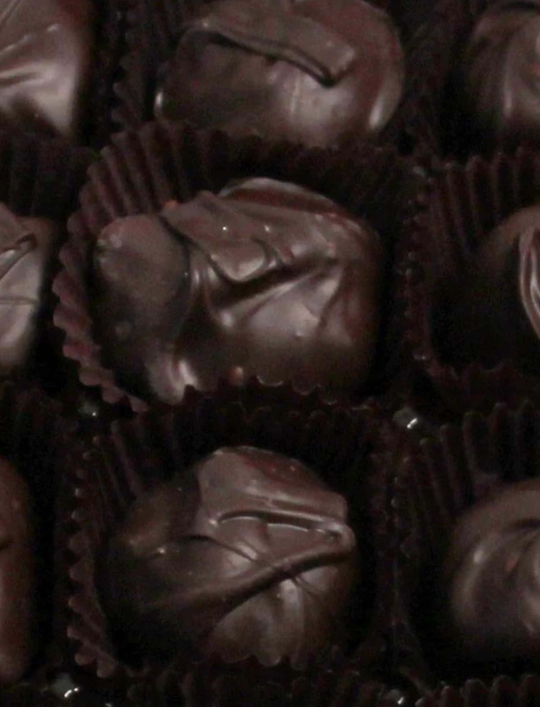 Dark Chocolate 桌布 壁紙 — 濃郁的黑松露巧克力放在深棕色紙杯中，在溫暖昏暗的燈光下。