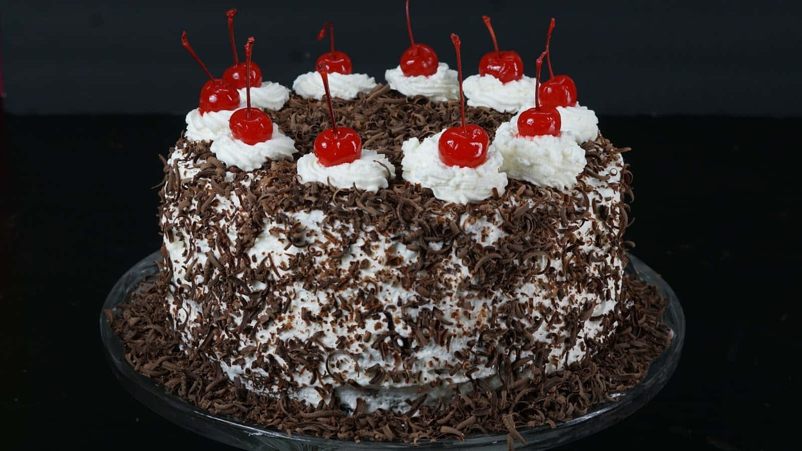 Black Forest Cake 桌布 壁紙 — 濃郁的黑櫻桃蛋糕，上面鋪滿鮮奶油和光澤的櫻桃，襯托深色背景。