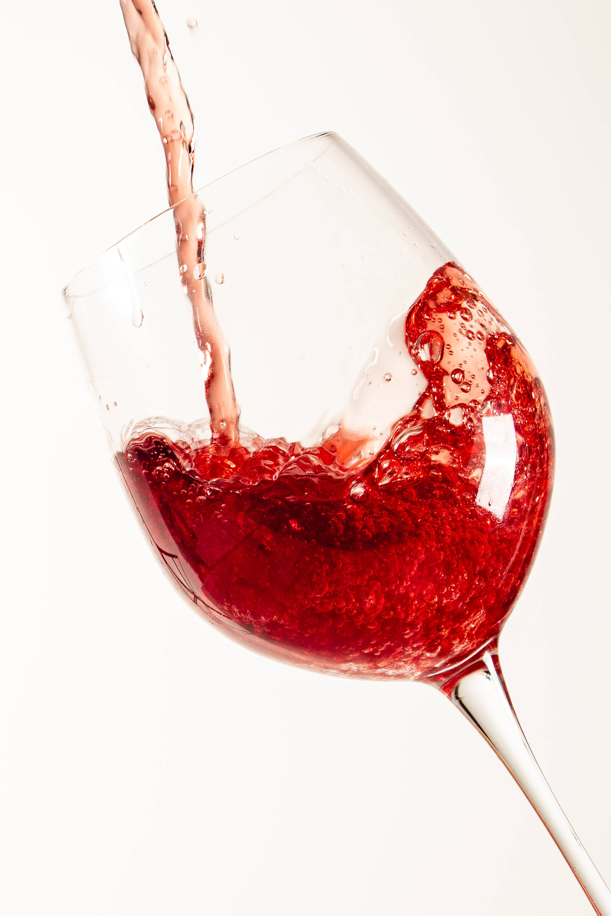 葡萄酒 桌布 壁紙 — 濃郁紅酒動態倒入透明玻璃杯中，在純白背景下產生閃爍氣泡和液體流動。