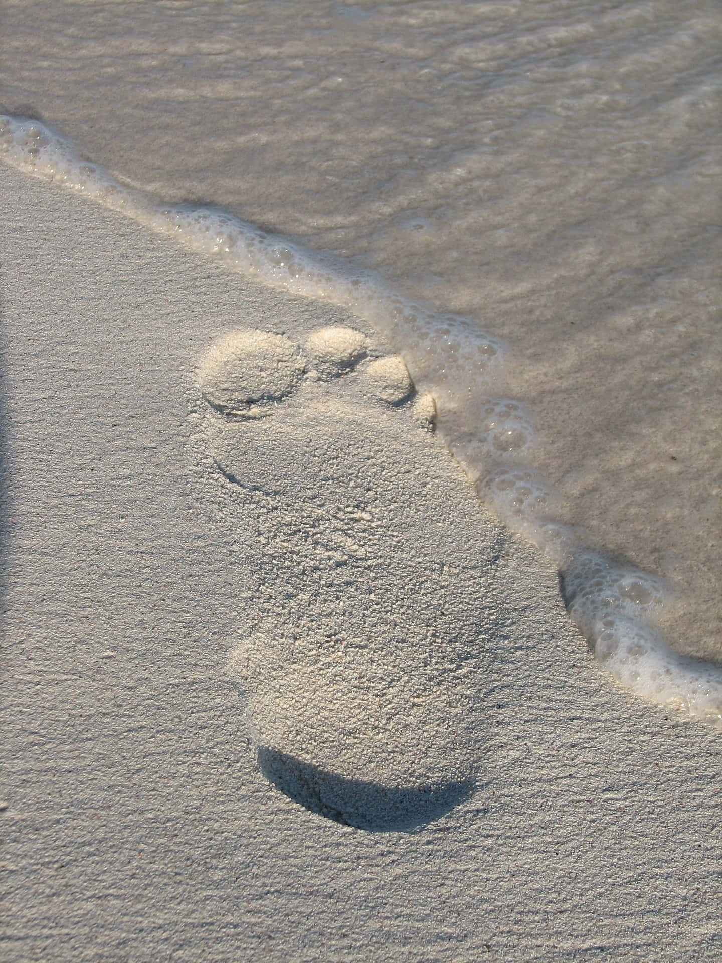 sand 桌布 壁紙 — 濕沙上一個赤腳印，溫柔的海浪在它周圍拍打。