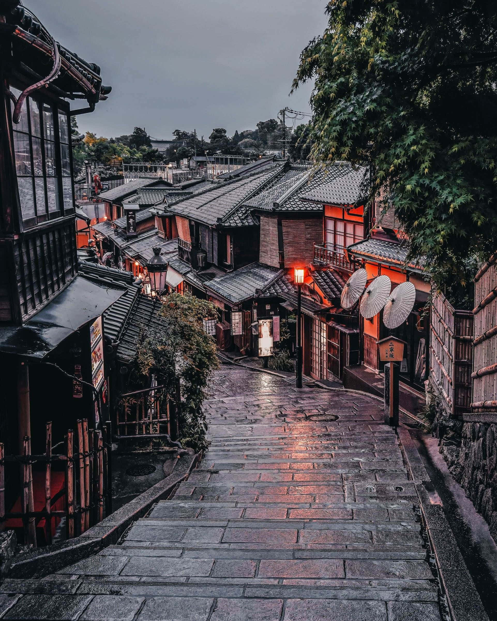 日本 桌布 壁紙 — 濕滑的石階蜿蜒穿過傳統日本木建築，在陰天下散發著溫暖的燈籠光芒。