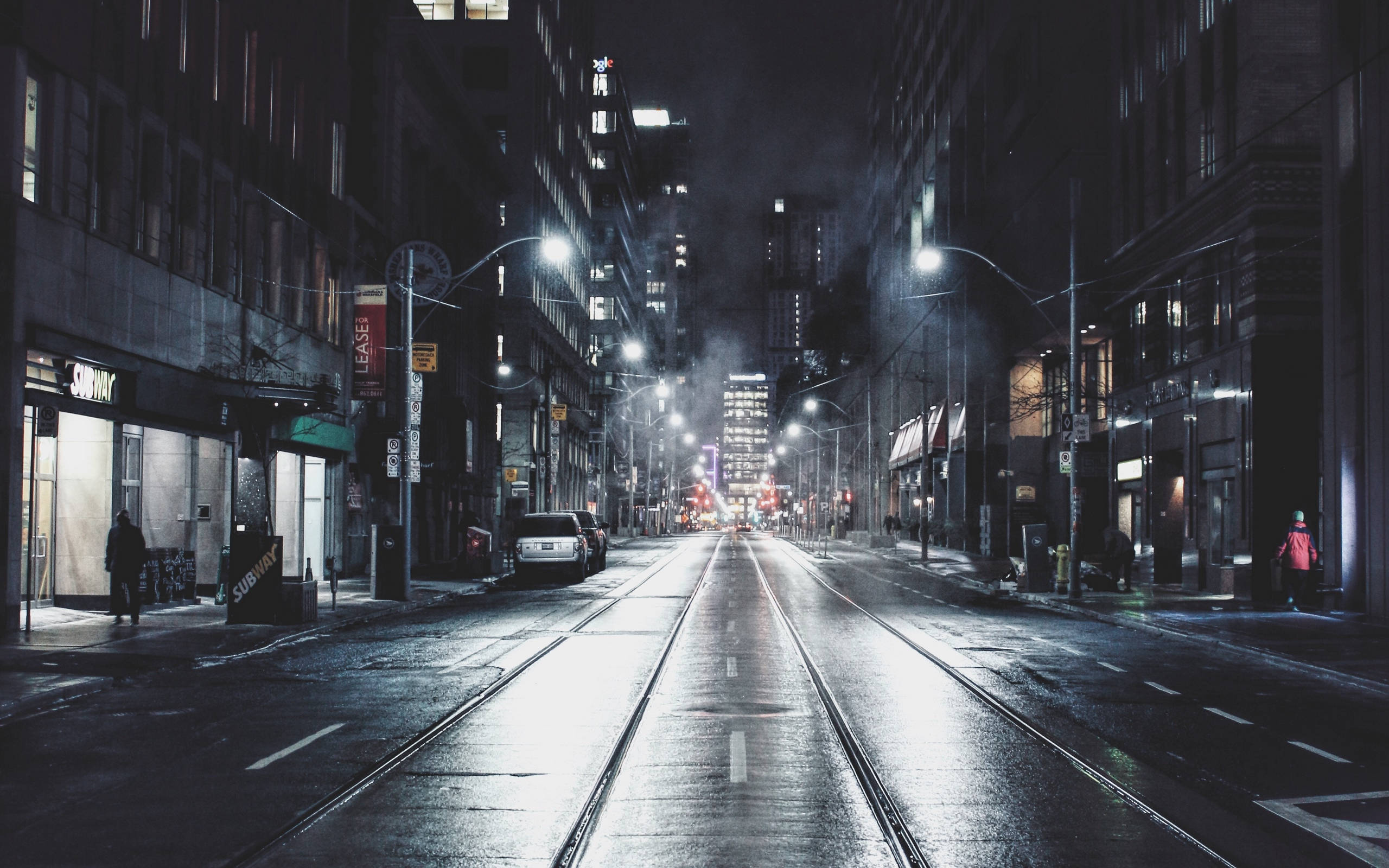 Toronto 桌布 壁紙 — 濕漉漉的城市街道在夜晚反射出閃爍的路燈和遠處的車流，聳立的建築物下。