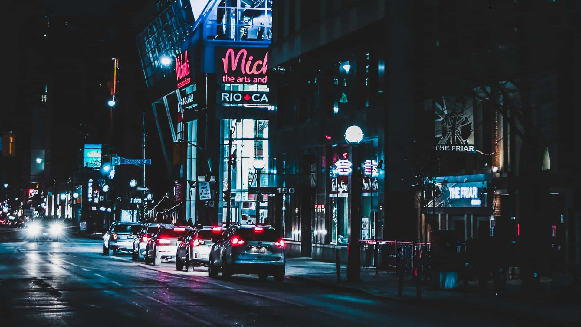 Dark Crossroad 桌布 壁紙 — 濕漉漉的城市街道在夜晚被鮮豔的霓虹招牌和發光的汽車尾燈照亮，倒映在路面上。