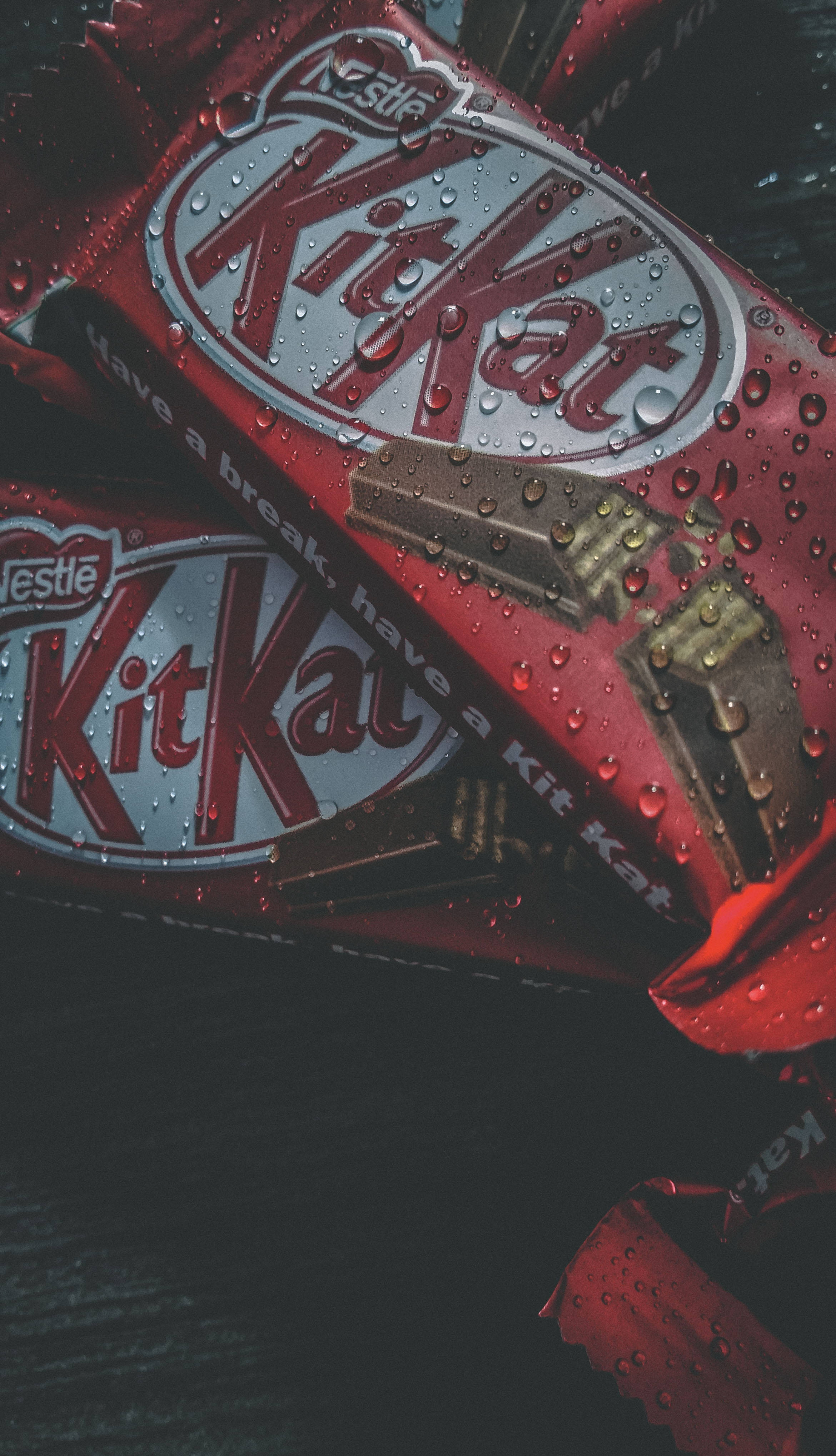 Chocolate 桌布 壁紙 — 濕紅色KitKat巧克力棒的特寫，水珠在錫箔包裝上閃閃發光。