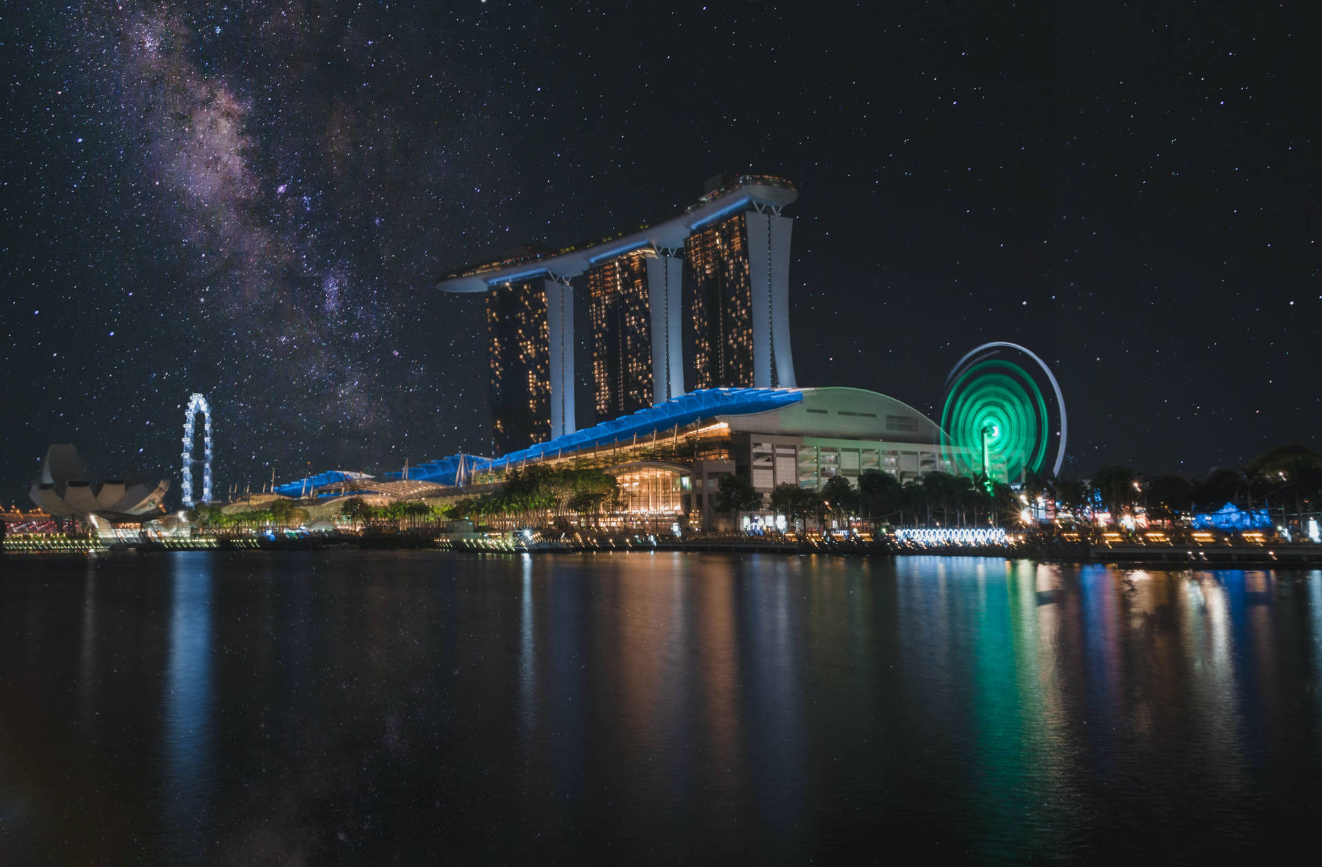 夜晚的濱海灣金沙，銀河系在上方，城市燈光倒映在水中。 — 風景動畫 壁紙
