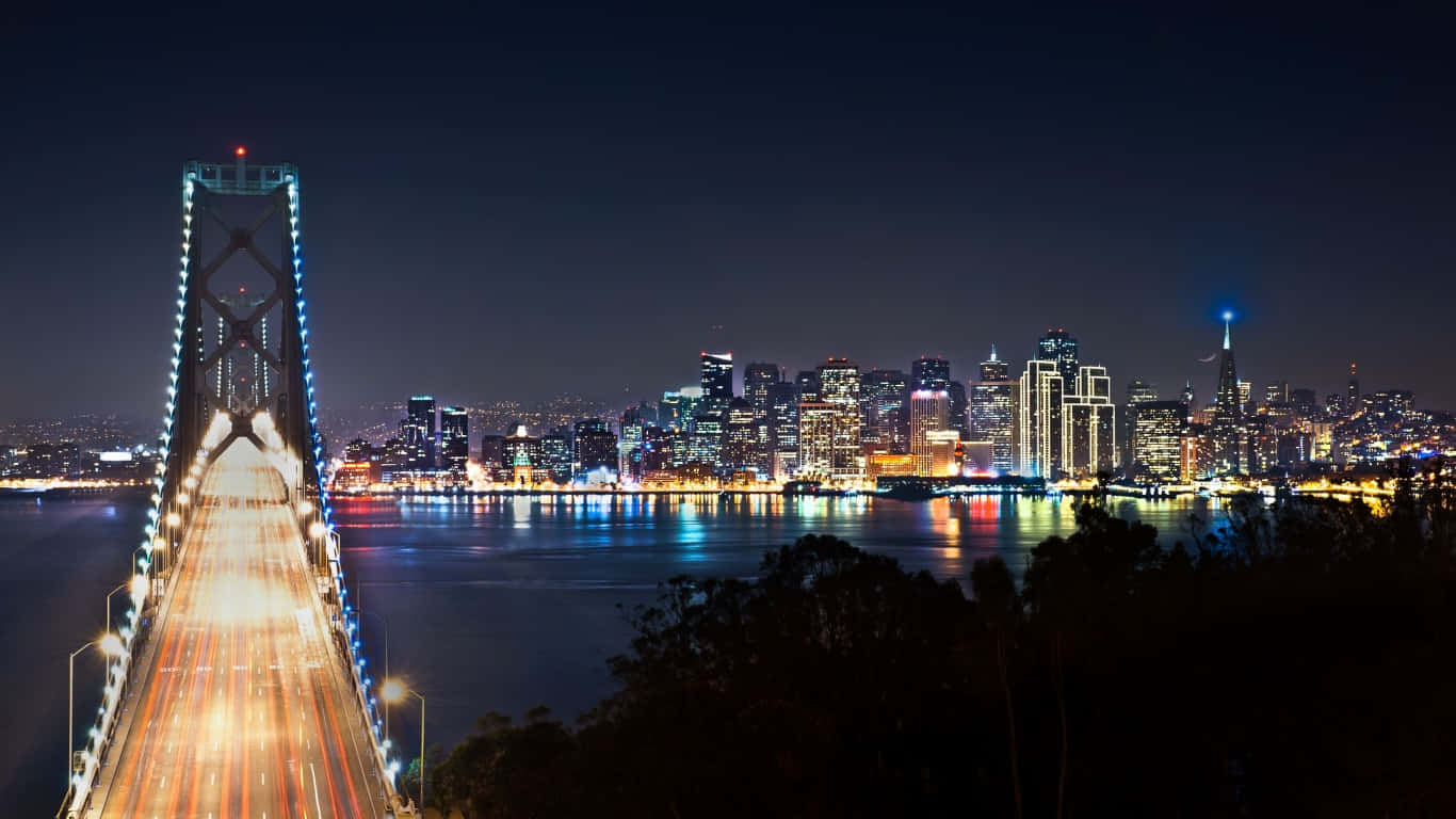 1366x768 San Francisco 桌布 壁紙 — 灣區大橋和舊金山天際線的迷人夜景，車流的光跡和閃爍的城市燈光倒映在水面上。