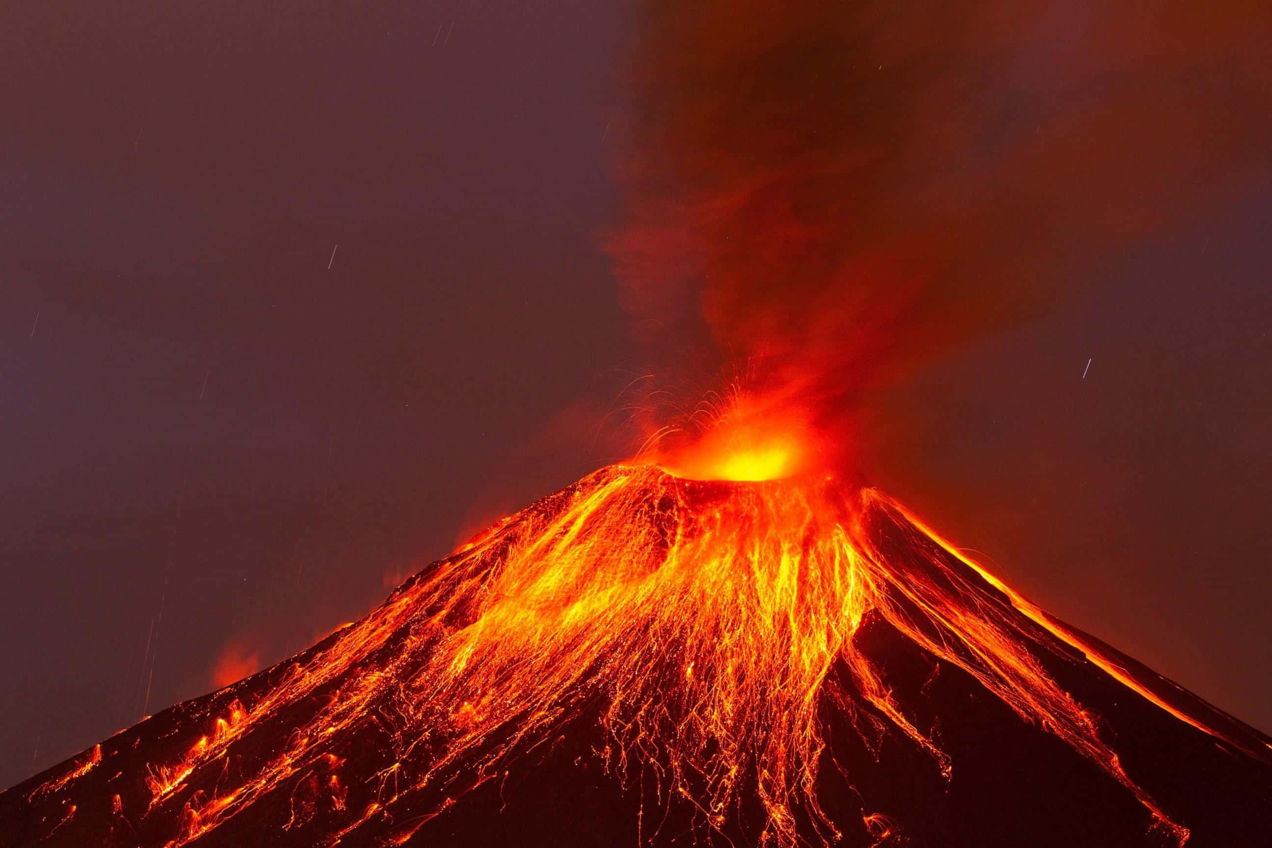 Volcano 桌布 壁紙 — 火山在夜間猛烈爆發，熾熱的熔岩沿著山坡流下，映襯著黑暗的天空。