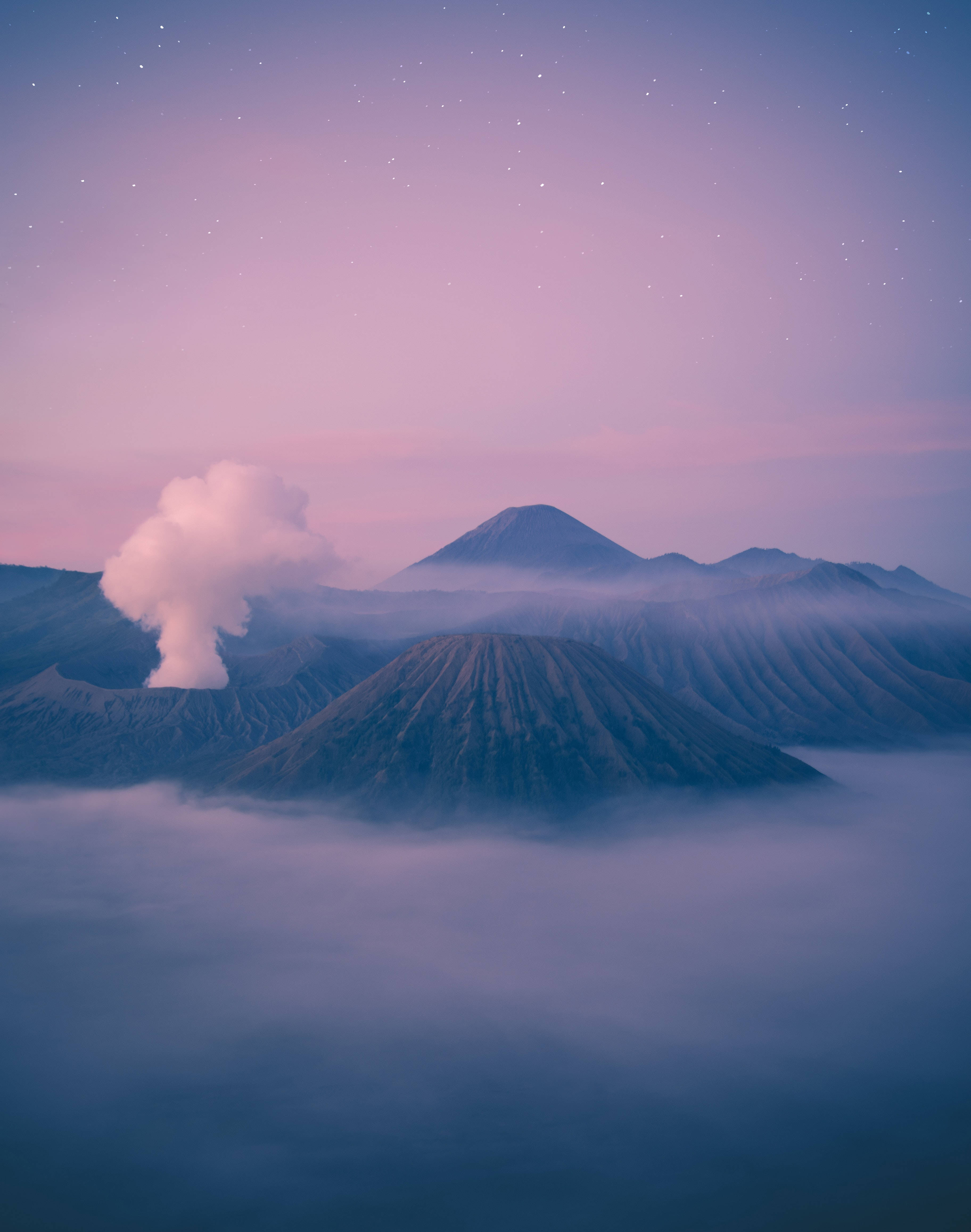 pastel 桌布 壁紙 — 火山從雲海中升起，在繁星點點的粉紫暮色天空下