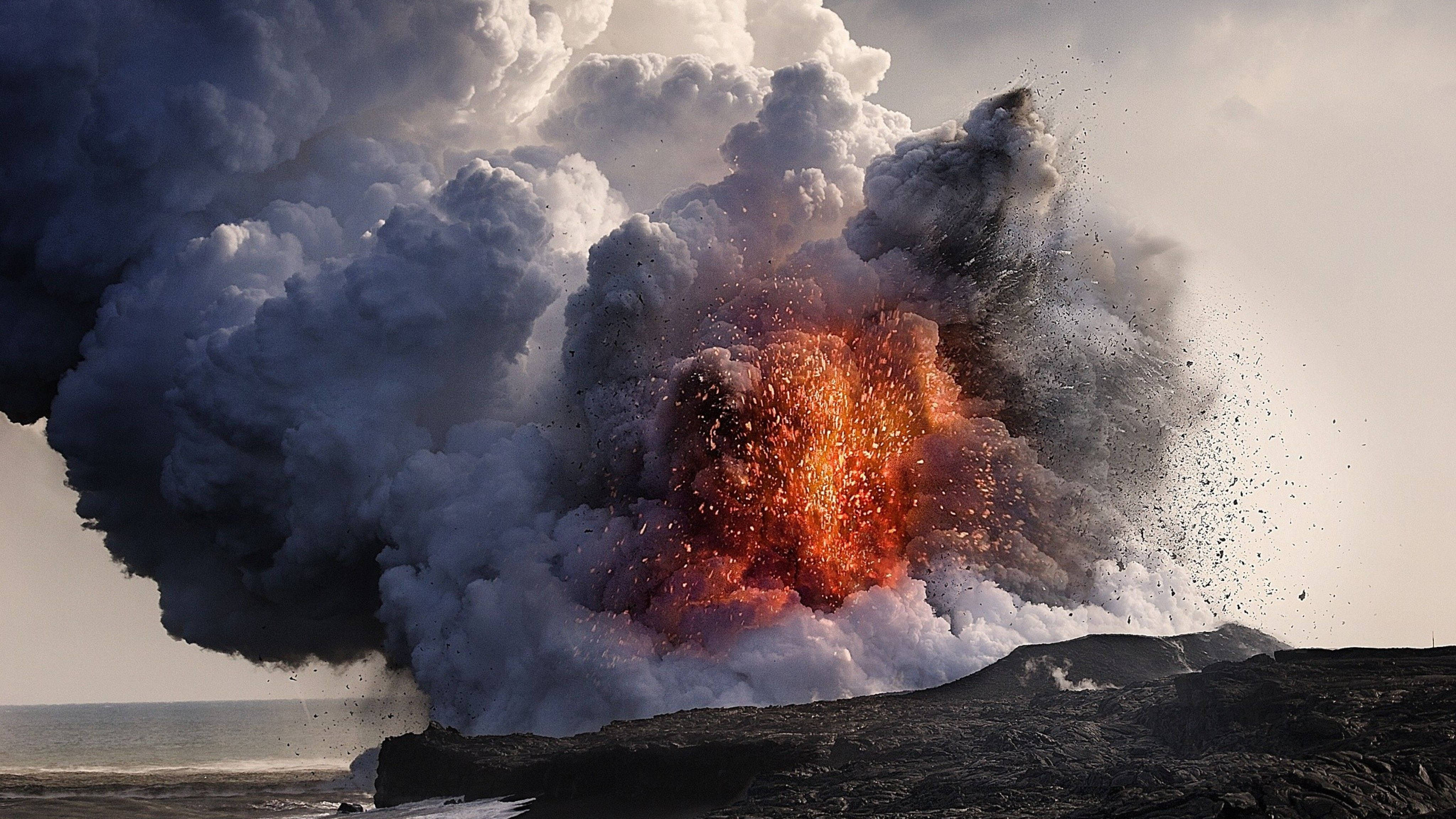 Retina 桌布 壁紙 — 火山爆發將熾熱的橙色熔岩和濃厚的灰色煙霧噴向崎嶇海岸線的天空。
