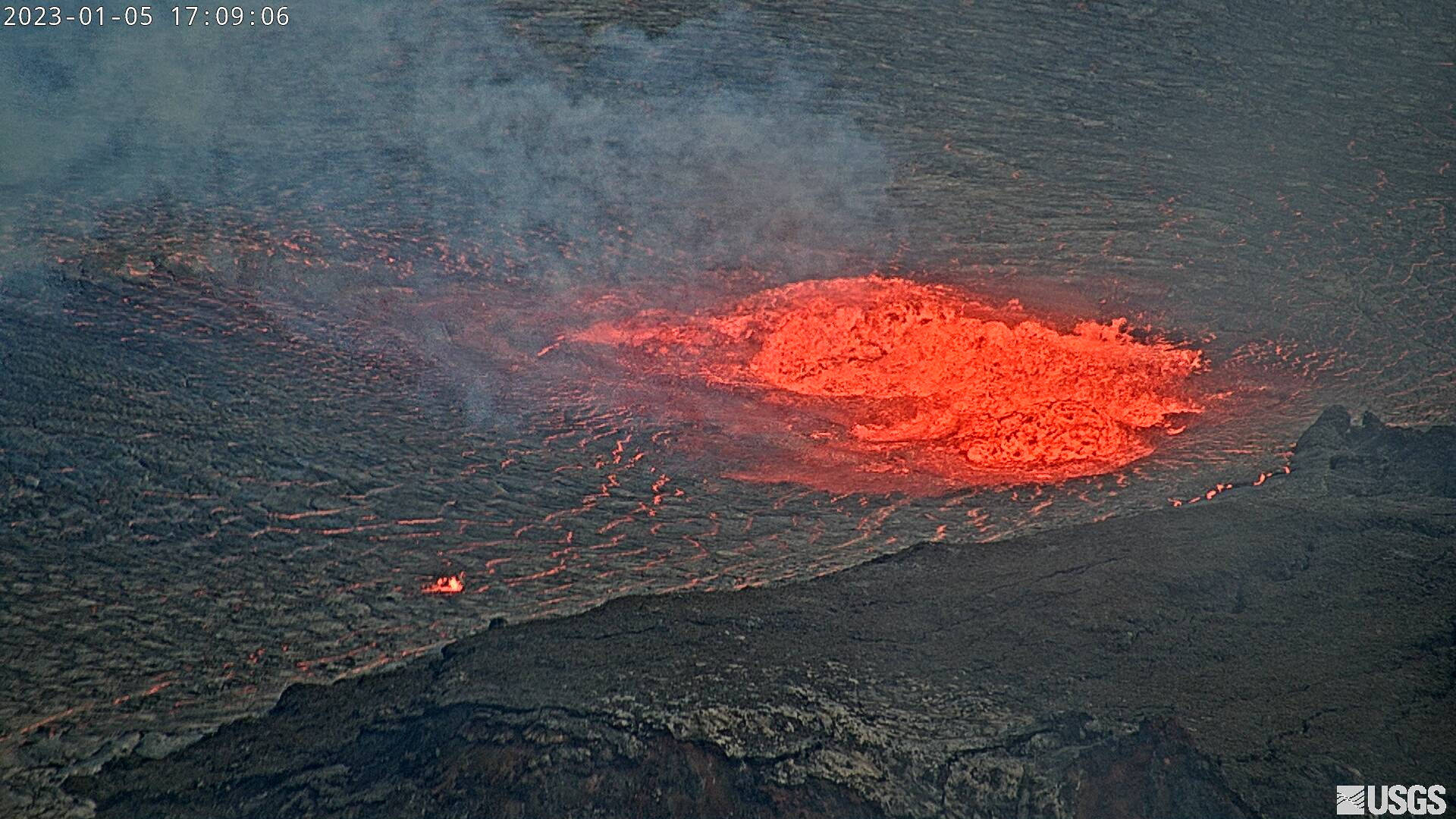 Volcano 桌布 壁紙 — 火山爆發的鳥瞰圖，發光的橙色熔岩在煙霧繚繞的天空下流過黑暗崎嶇的地形。