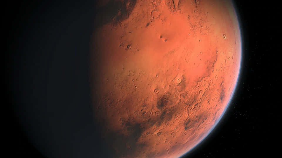 Mars Planet 桌布 壁紙 — 火星在深空中發光的特寫視圖，其鏽蝕表面和佈滿隕石坑的地形被一層薄薄的藍色大氣輝光照亮。