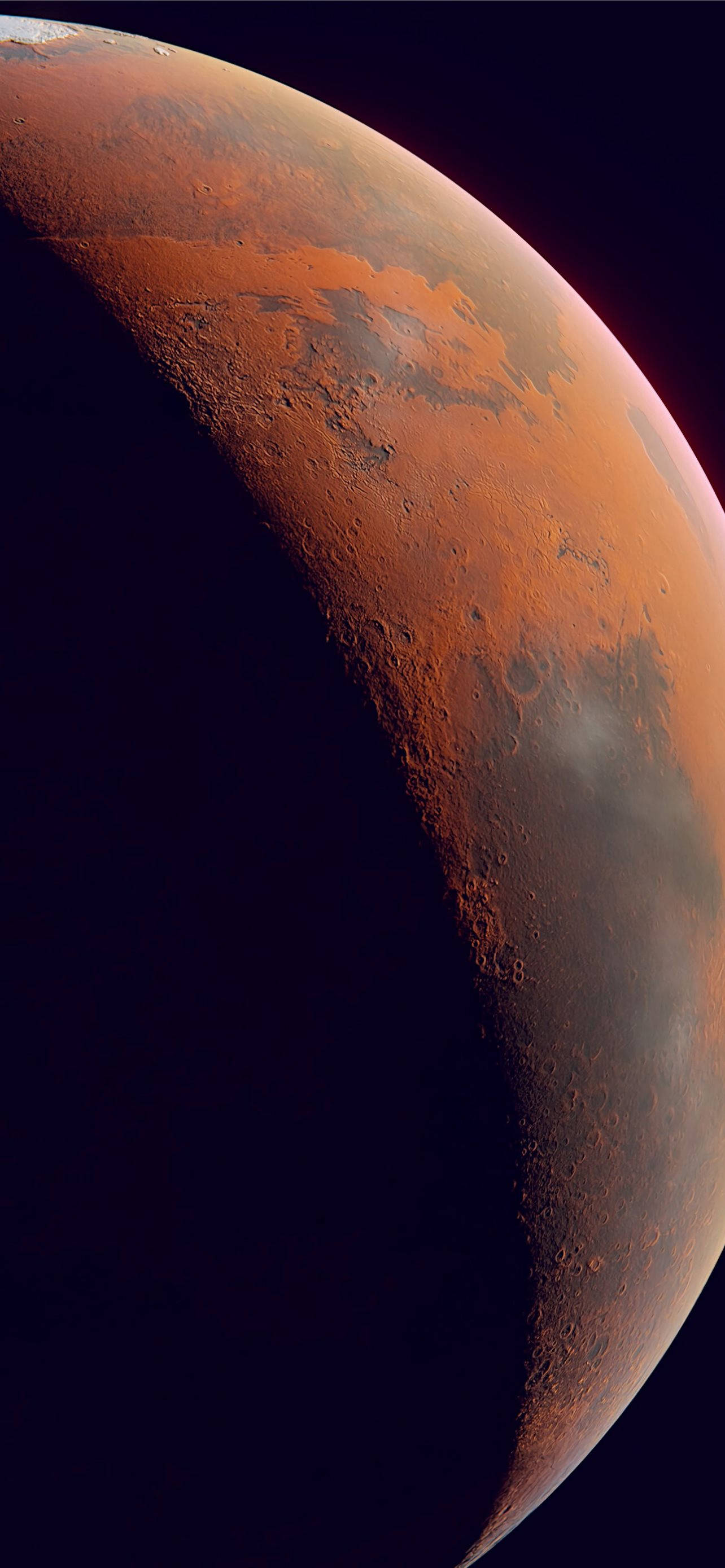 Mars iPhone 桌布 壁紙 — 火星戲劇性的新月形狀在太空的黑色虛空中發出鏽橙色光芒，揭示了佈滿隕石坑的地形和大氣薄霧。