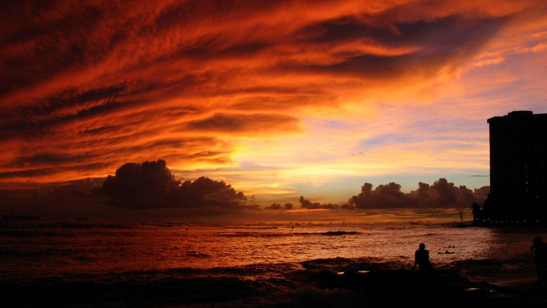 在戲劇性的雲層和海浪中，火熱的日落海灘上的人們剪影。 — 風景動畫 壁紙