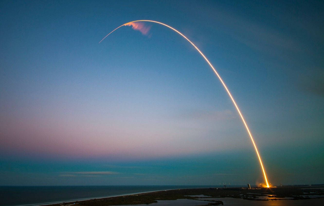 SpaceX 桌布 壁紙 — 火箭在暮色天空中劃出燦爛的火弧，升越沿海水域。