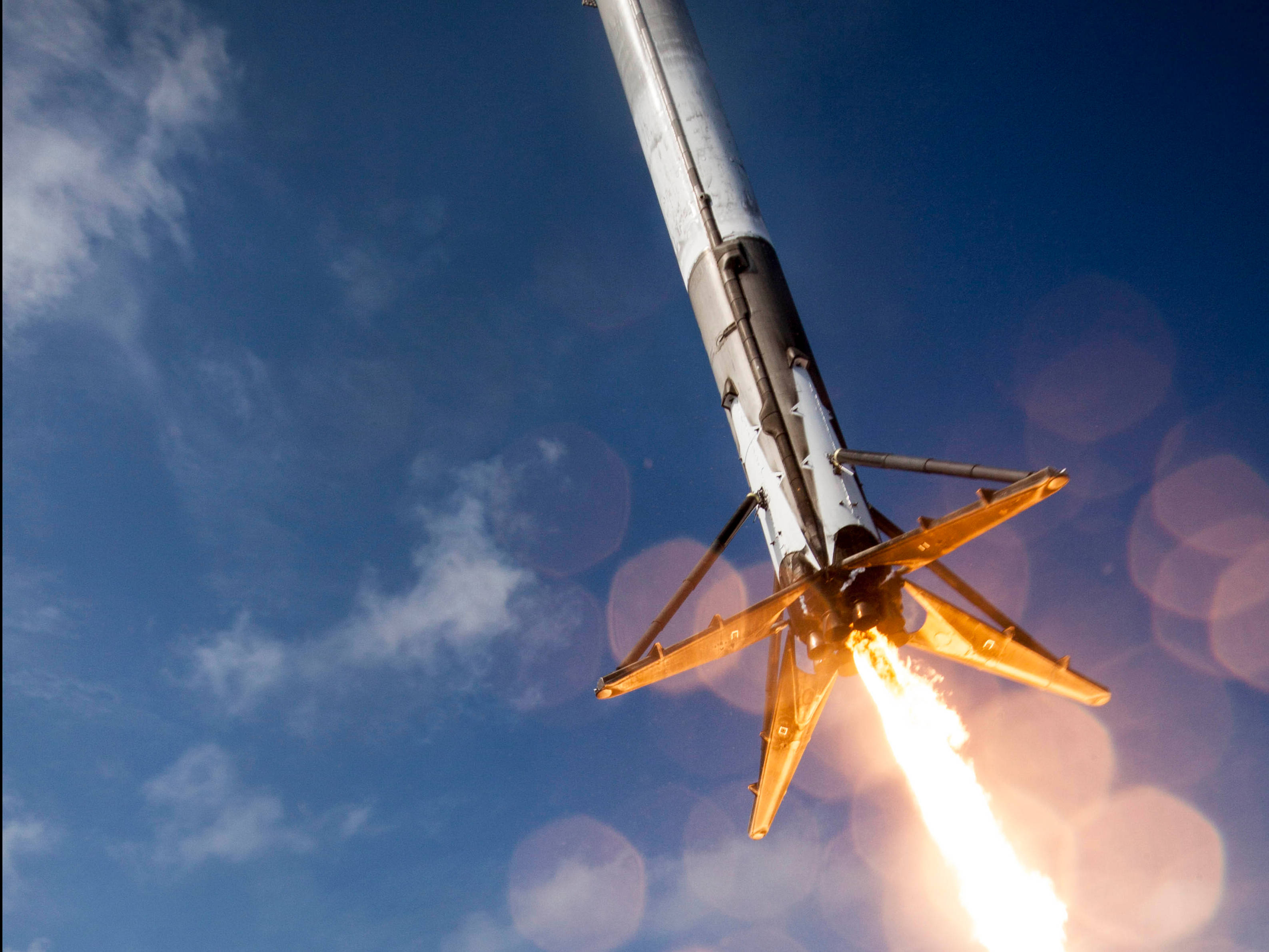 SpaceX 桌布 壁紙 — 火箭強力升空，劃破清澈藍天，伴隨熾熱尾焰和鏡頭眩光。
