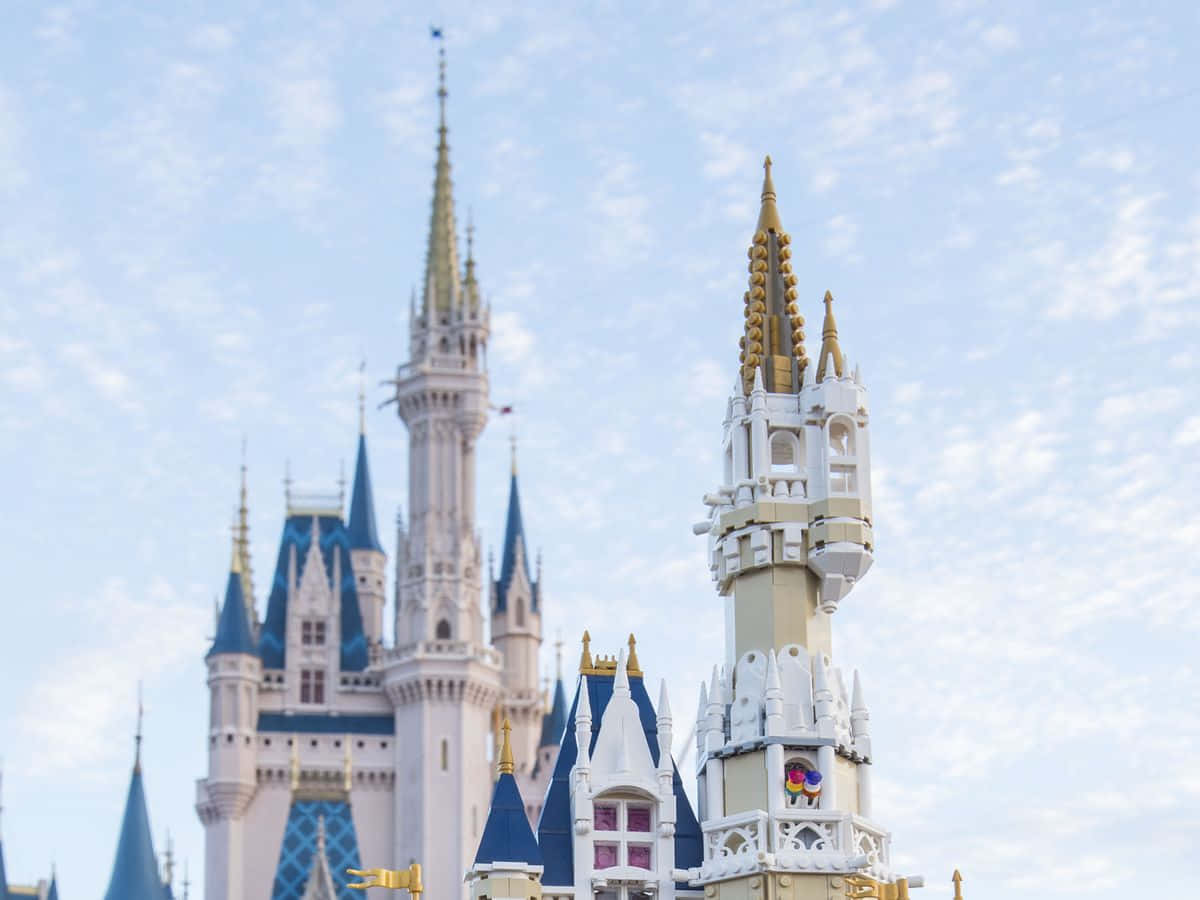 Disney Castle 桌布 壁紙 — 灰姑娘城堡的LEGO複製品在前景，真實城堡在後方模糊，襯著柔和藍天。