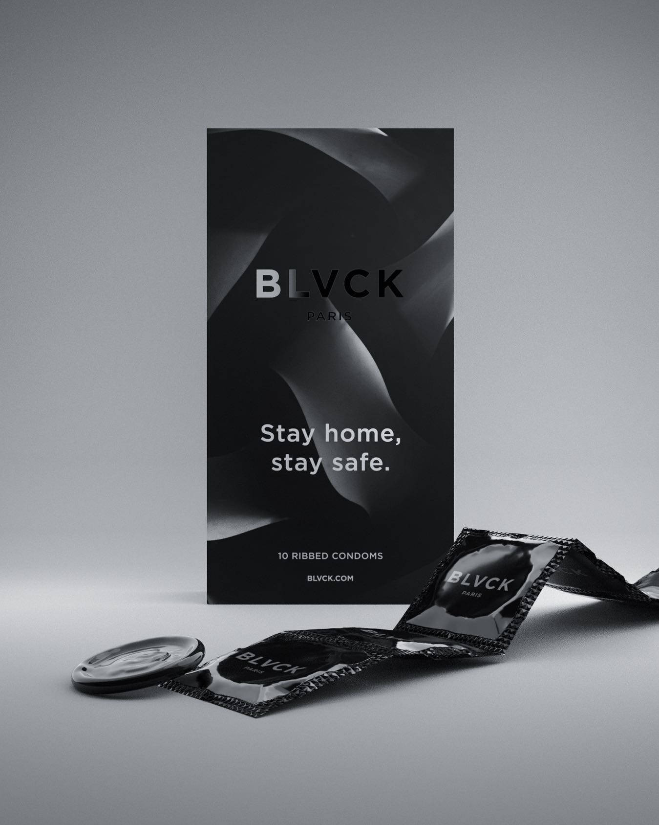 Blvck Paris 桌布 壁紙 — 灰色工作室背景上，BLVCK Paris 保險套的簡約黑白產品照，搭配時尚包裝和散落的錫箔包裝。
