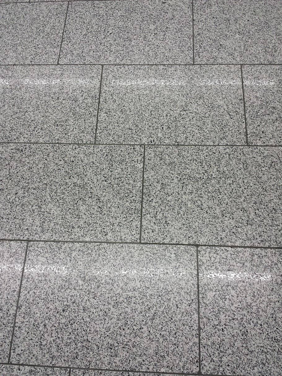 Floor Tiles 桌布 壁紙 — 灰色斑點花崗岩瓷磚的特寫，帶有深色填縫線和明亮的光線反射。