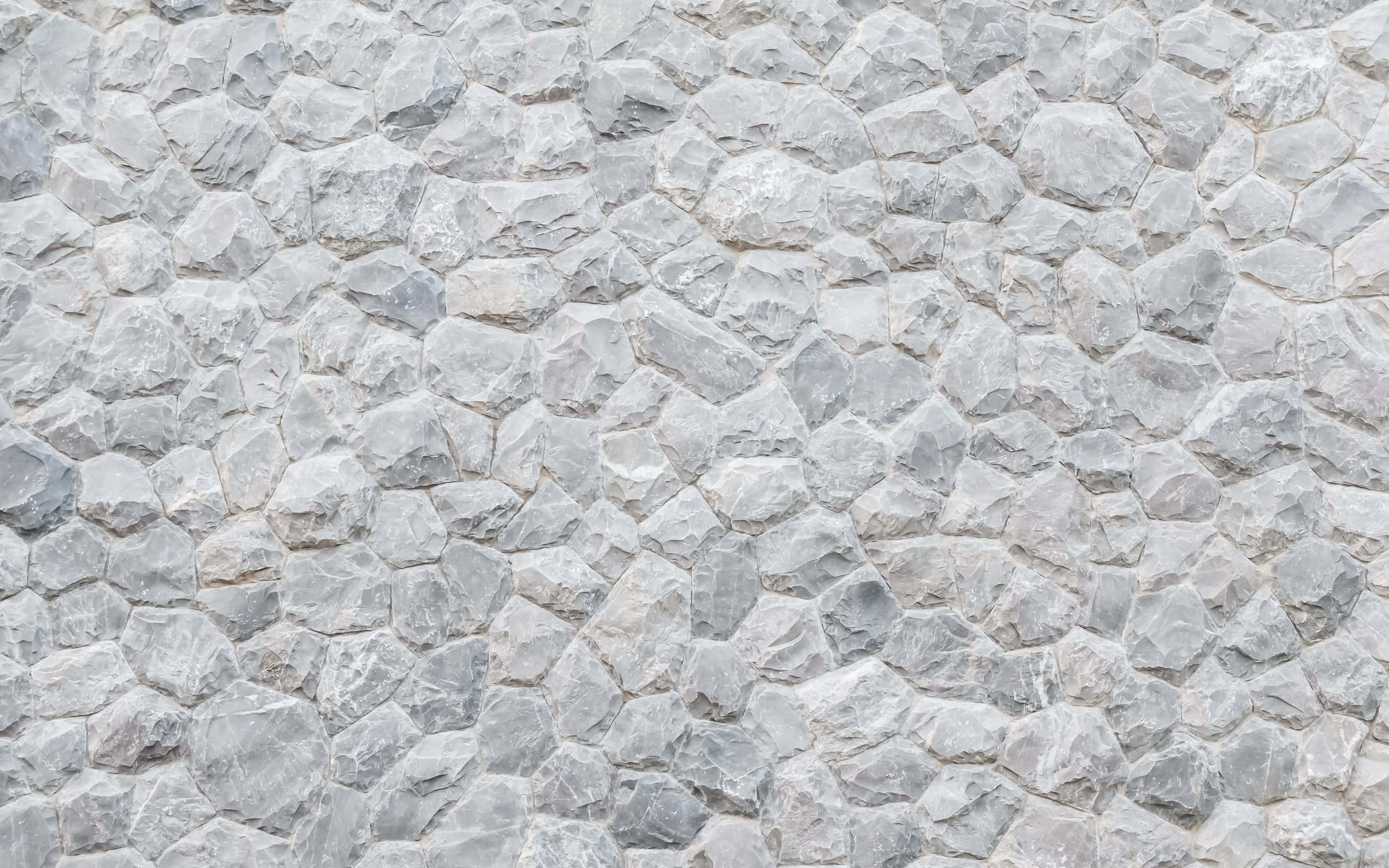 Stone Wall 桌布 壁紙 — 灰色石牆的特寫，具有不規則形狀的鵝卵石和自然風化的表面。