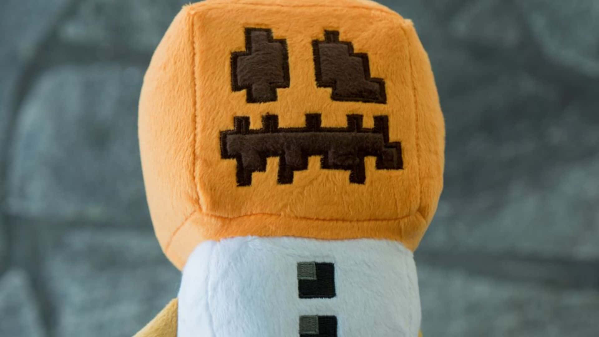 Minecraft Snow Golem 桌布 壁紙 — 灰色石頭背景上，一個像素化面孔的毛絨Minecraft南瓜頭的近距離特寫。