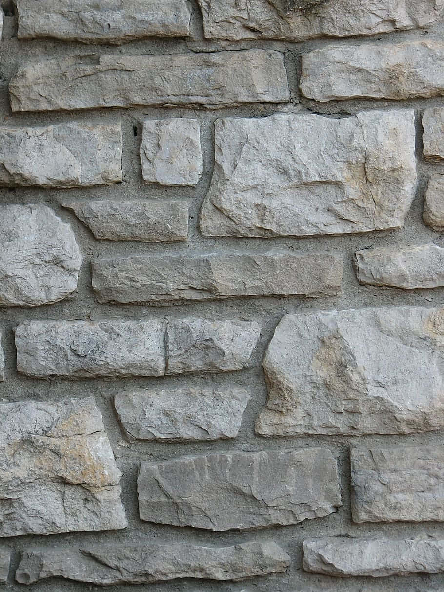 Brick Wall 桌布 壁紙 — 灰色砂漿中不規則灰色和米色石塊的質樸石牆特寫。