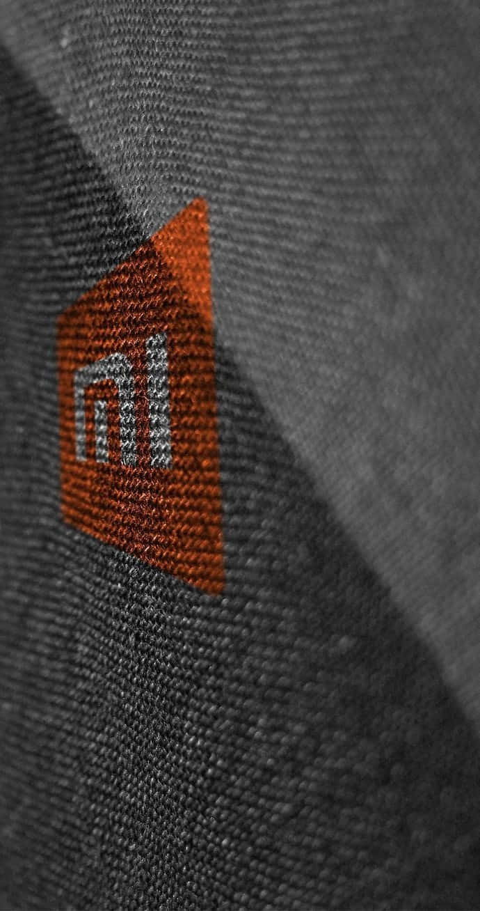 Xiaomi 桌布 壁紙 — 灰色紋理布料的特寫，帶有橙色刺繡的Xiaomi標誌，對焦清晰。