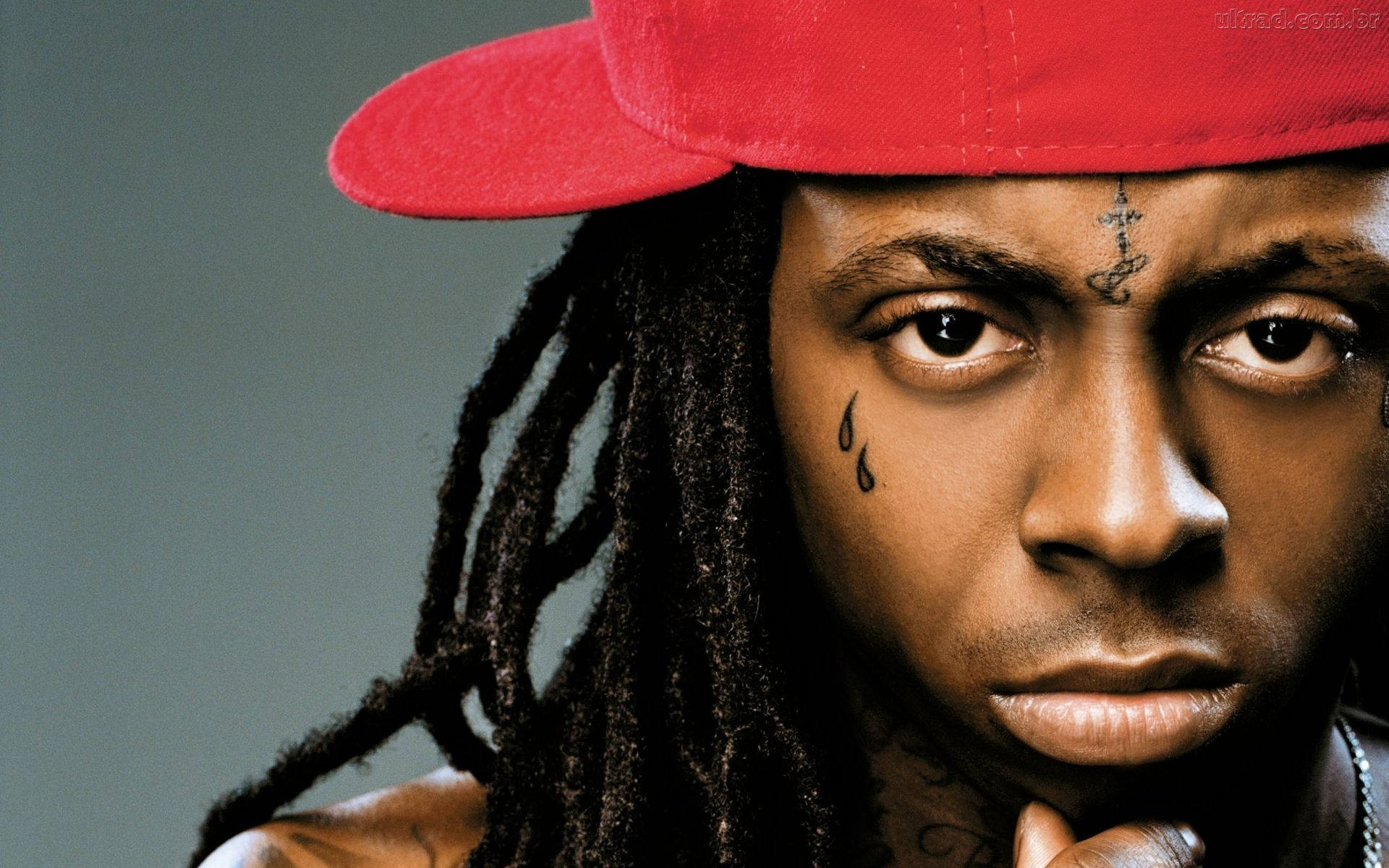 Lil Wayne 桌布 壁紙 — 灰色背景前，一名留著辮子、戴紅色帽子、臉上有刺青的男子特寫肖像。