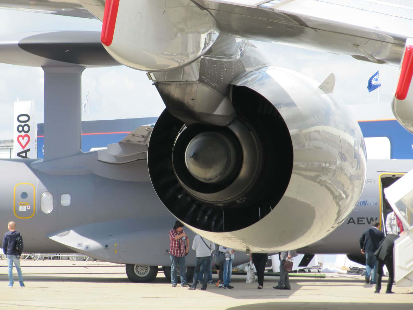 Aircraft 桌布 壁紙 — 灰色軍用運輸機上大型噴射引擎的特寫，人們在明亮的日光下於航空展觀看。