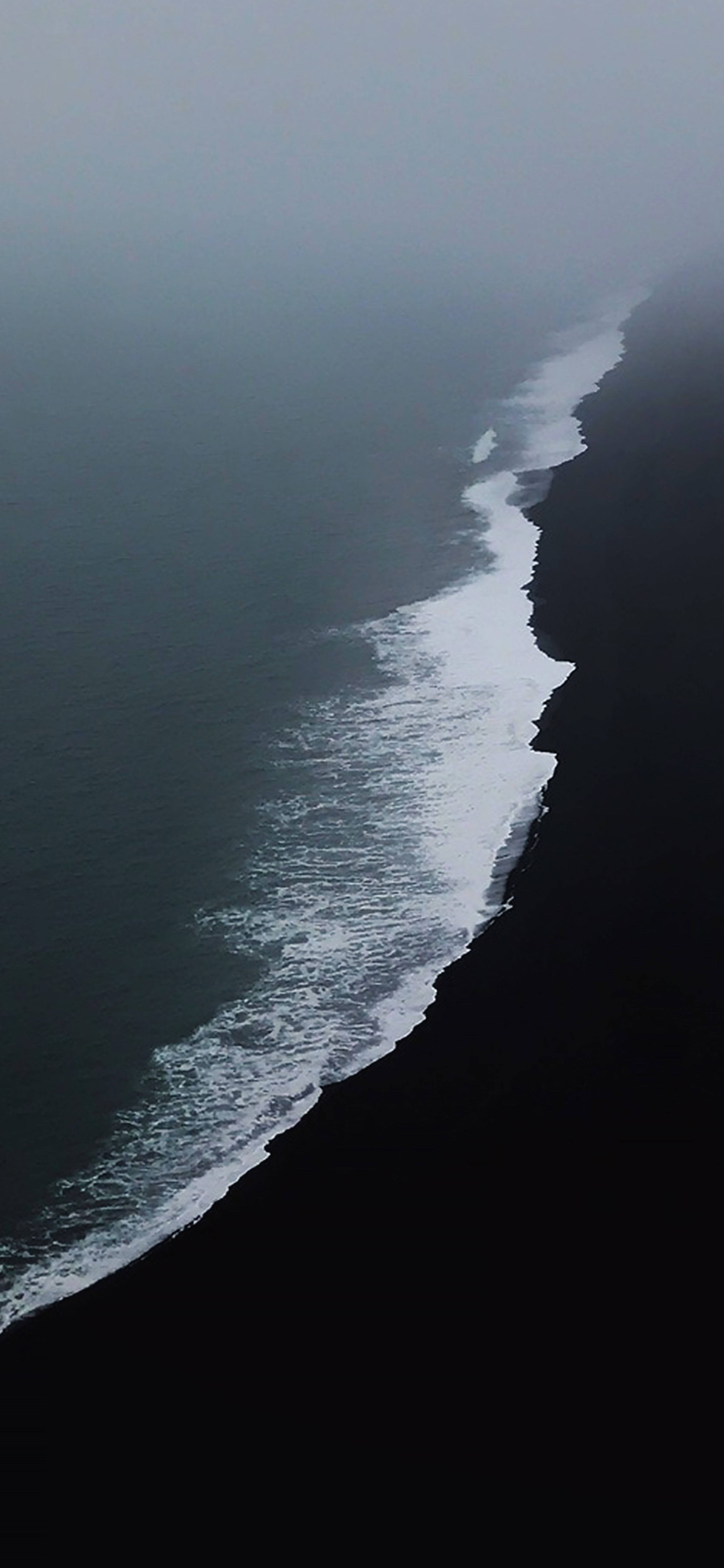冰島 桌布 壁紙 — 灰色迷霧天空下，海浪沖擊黑色火山沙灘的航拍視圖。
