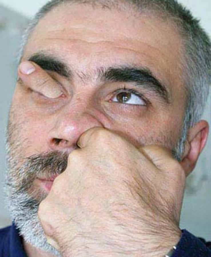 meme 桌布 壁紙 — 灰髮鬍鬚男子用手遮嘴眨眼的特寫。