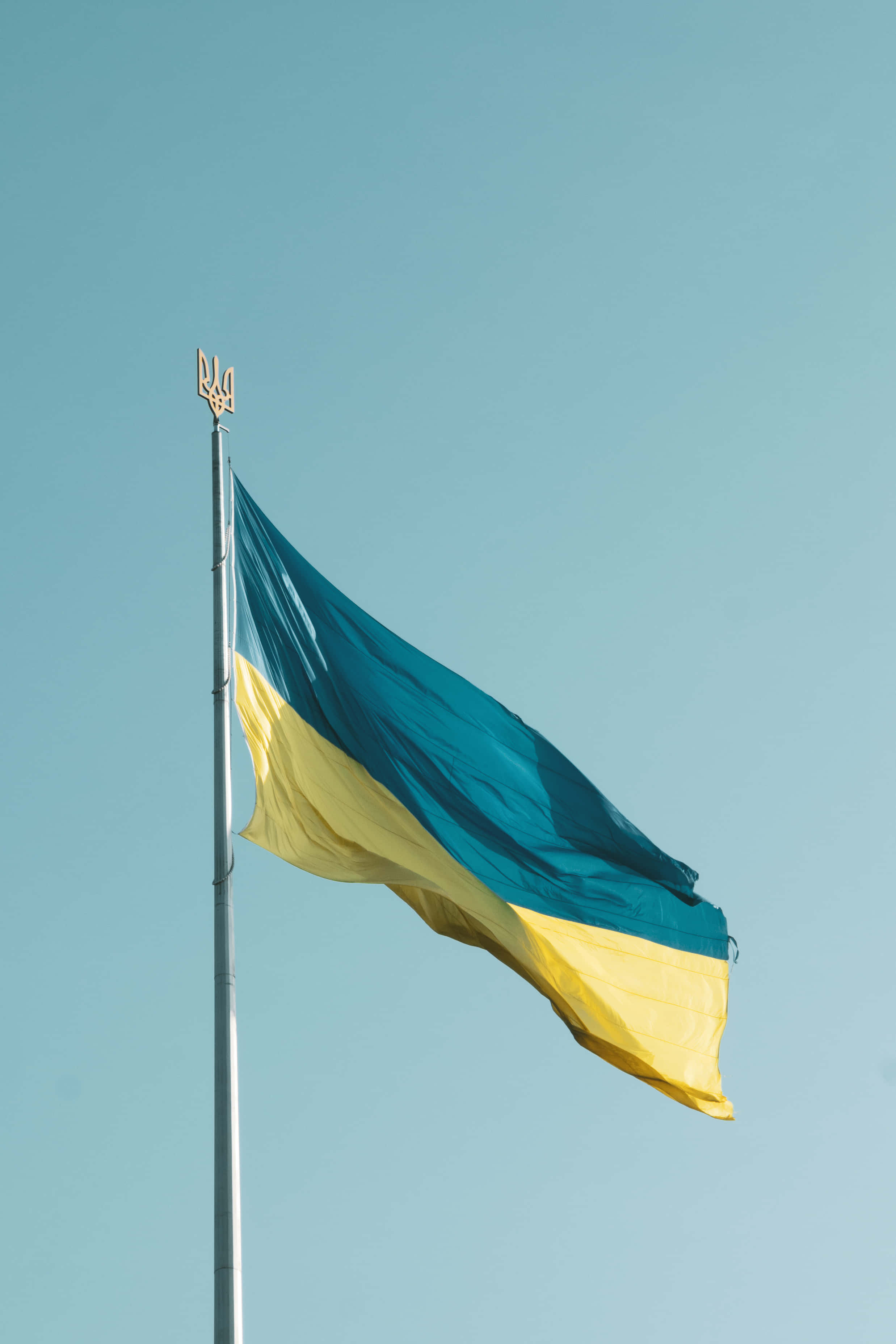 Ukraine 桌布 壁紙 — 烏克蘭國旗上的藍黃條紋在晴朗的天空下在旗桿上自豪地飄揚。