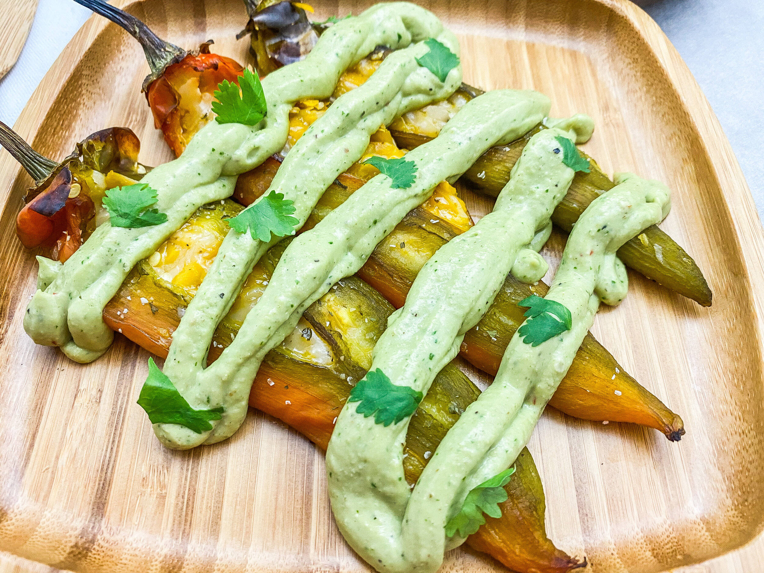 Mexican Food 桌布 壁紙 — 烤彩色甜椒淋上奶油綠色醬汁，並以新鮮香菜點綴在木托盤上。