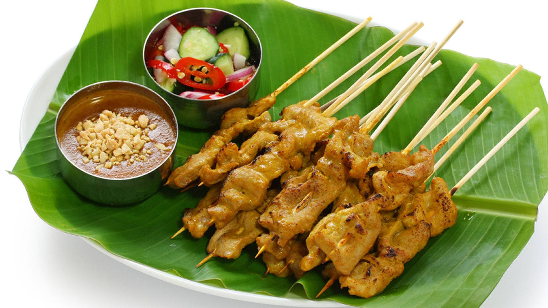 Delicious Food 桌布 壁紙 — 烤沙爹肉串搭配花生醬和黃瓜酸辣醬，盛放在新鮮香蕉葉上。