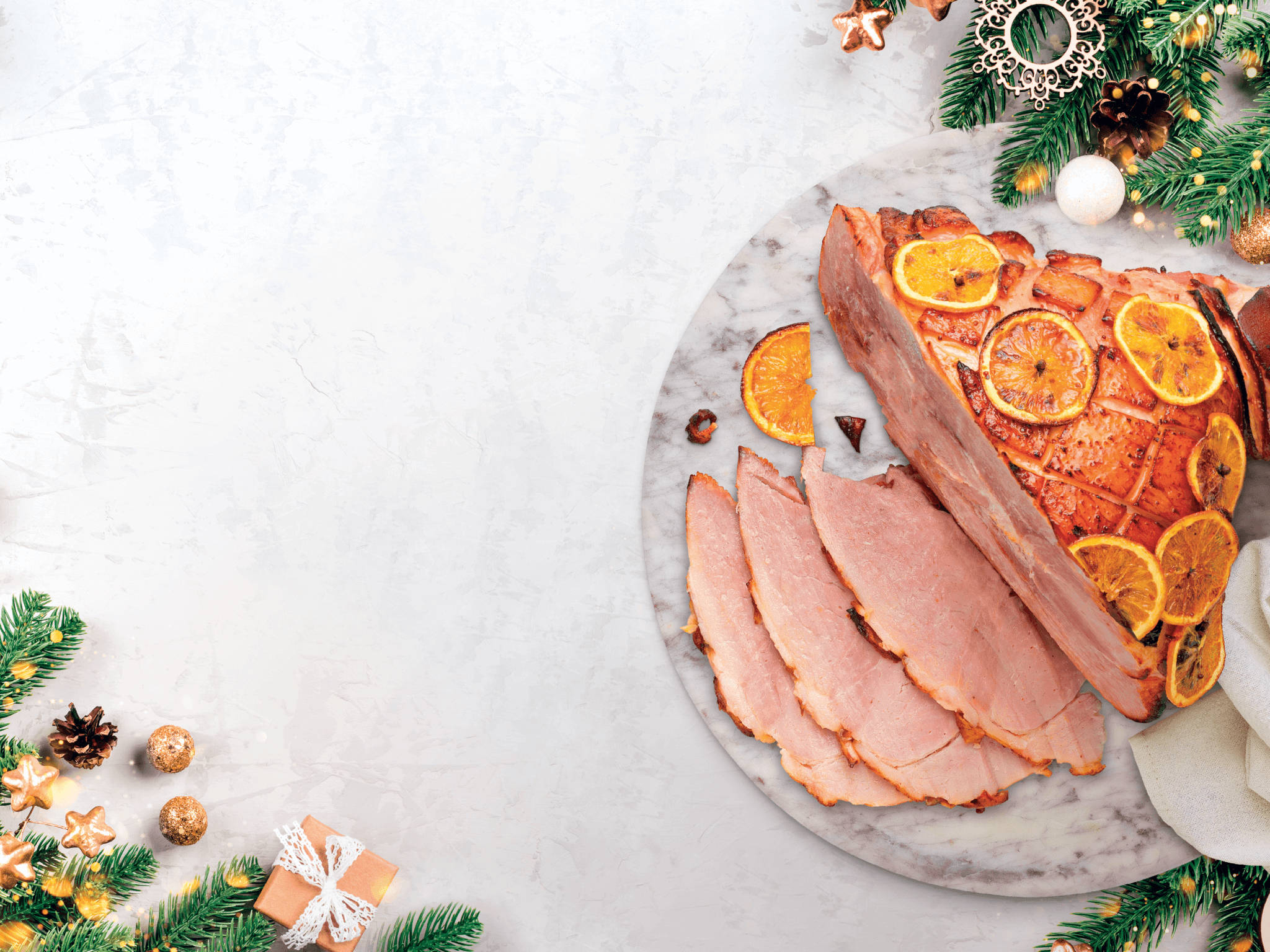 Ham 桌布 壁紙 — 烤火腿配上乾橙片，放在大理石托盤上，周圍環繞著節日松樹枝和聖誕裝飾。