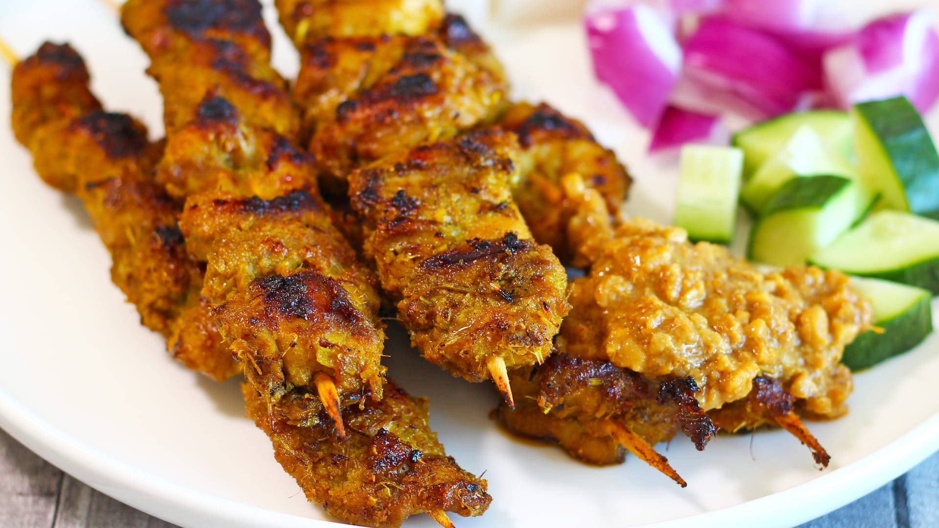 Delicious Food 桌布 壁紙 — 烤焦邊緣的烤肉串，盛載於白色盤子上，搭配切片小黃瓜和紅洋蔥。