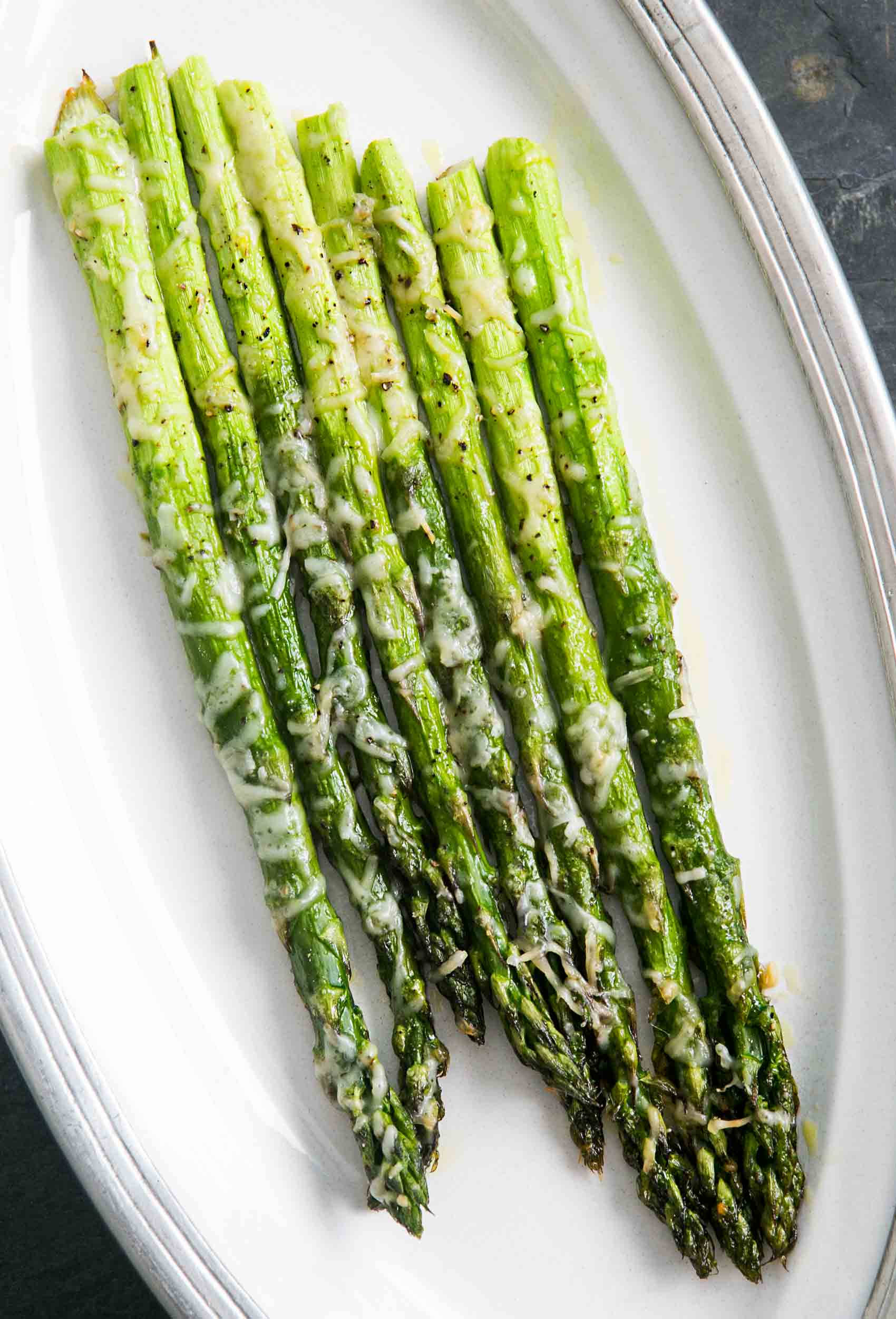 Healthy Food 桌布 壁紙 — 烤蘆筍尖，上面放有融化起司和黑胡椒，放在白色橢圓形盤子上。