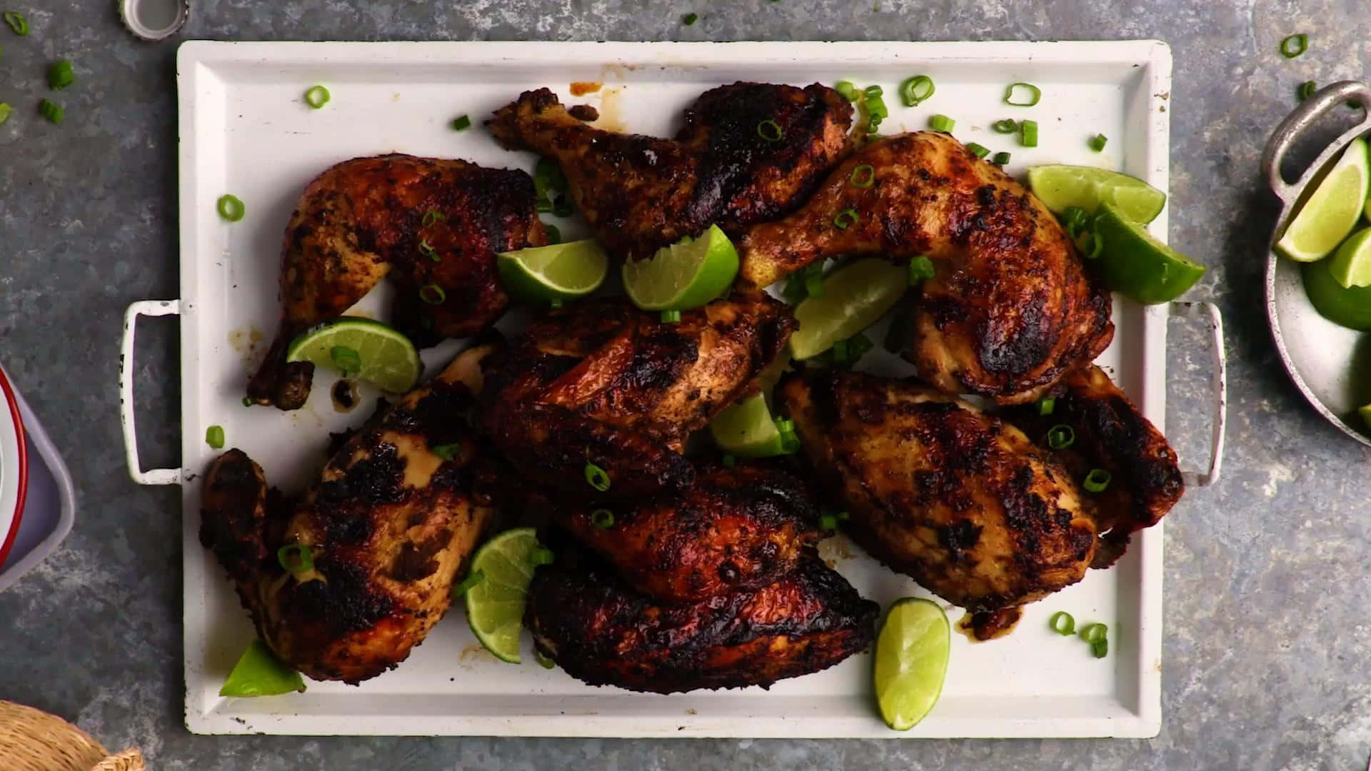 Blackened Chicken 桌布 壁紙 — 烤雞塊搭配萊姆角和切碎的青蔥，放在白色托盤上，灰色紋理背景。