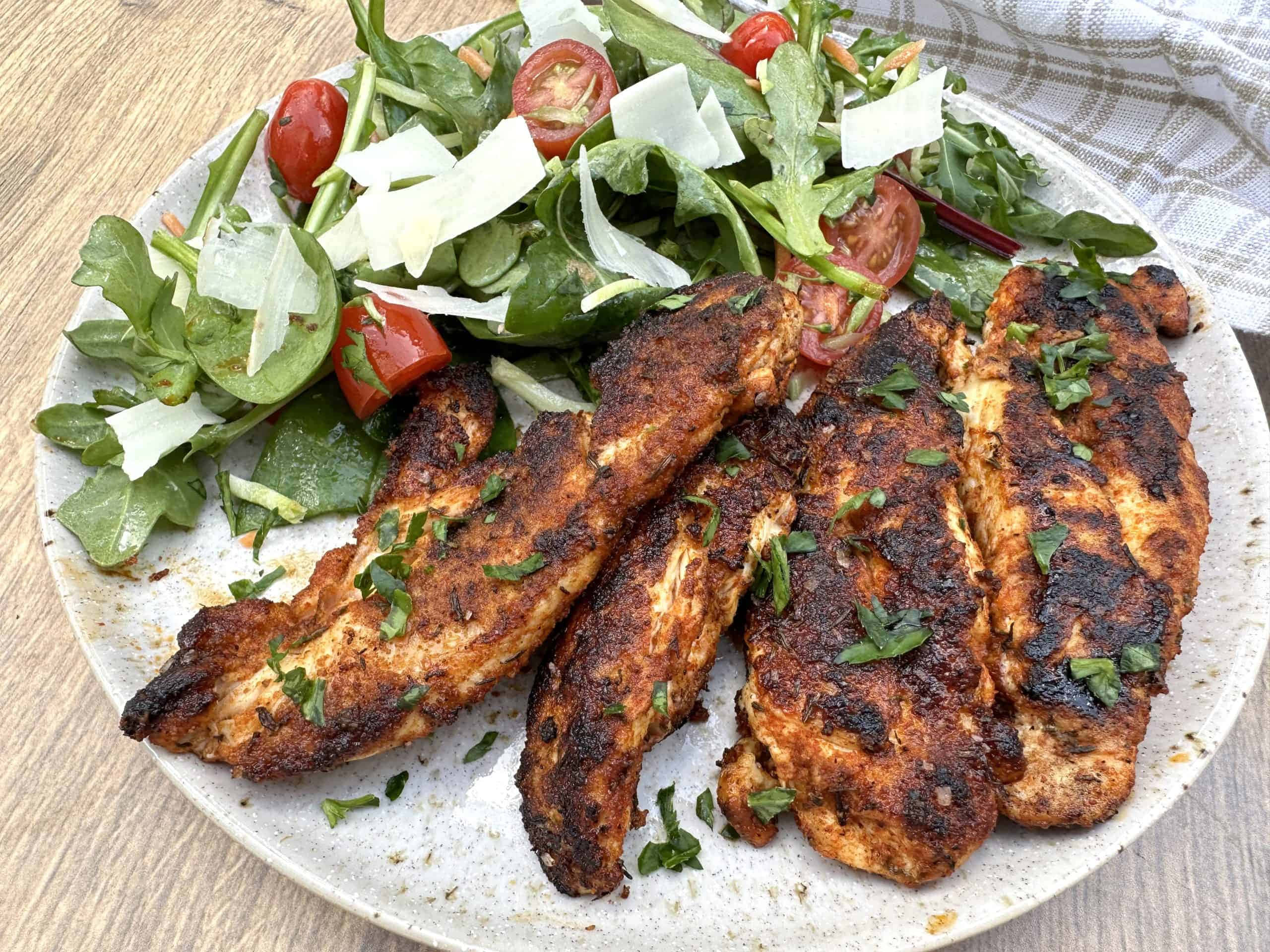 Blackened Chicken 桌布 壁紙 — 烤雞肉條配新鮮芝麻菜、櫻桃番茄和刨絲起司，放在斑點盤上。