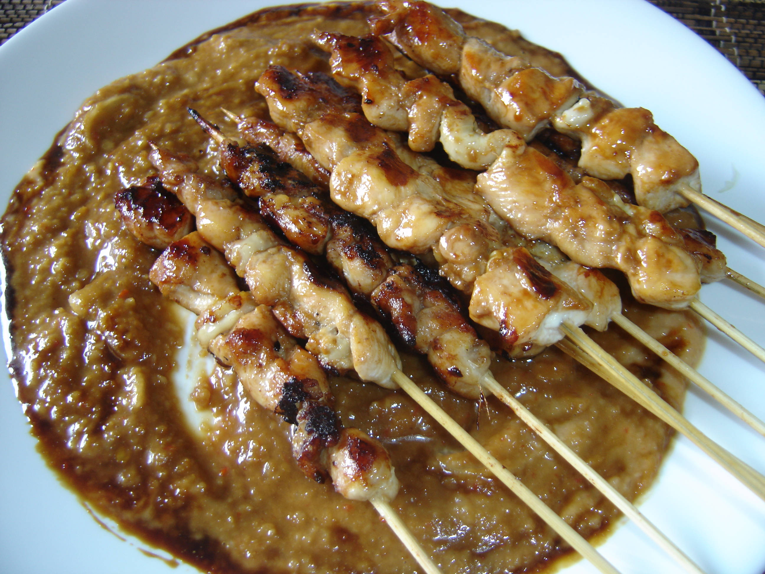 Delicious Food 桌布 壁紙 — 烤雞肉沙爹串在白色盤子上的濃厚花生醬池上閃爍著醬汁。