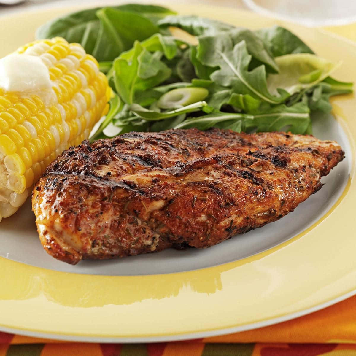 Blackened Chicken 桌布 壁紙 — 烤雞胸肉配玉米和芝麻菜沙拉，盛在黃色盤子上。