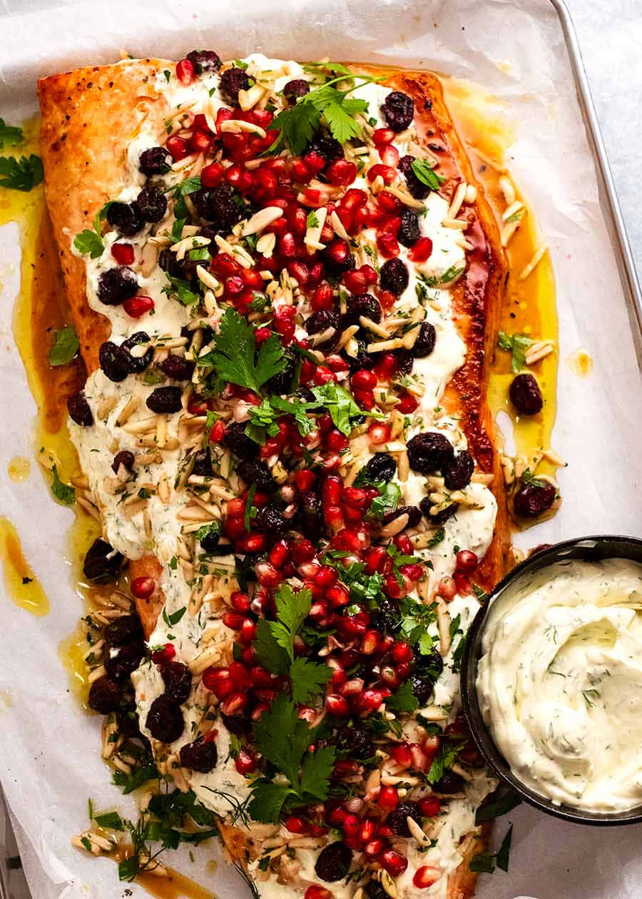 Salmon 桌布 壁紙 — 烤鮭魚菲力配上奶油醬汁、石榴籽、葡萄乾和新鮮香草，放在烘焙紙上。