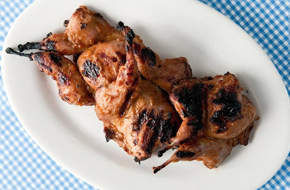 Quail 桌布 壁紙 — 烤鵪鶉串燒，表皮焦黑，放在白色盤子上，盤下是藍白格子桌布。
