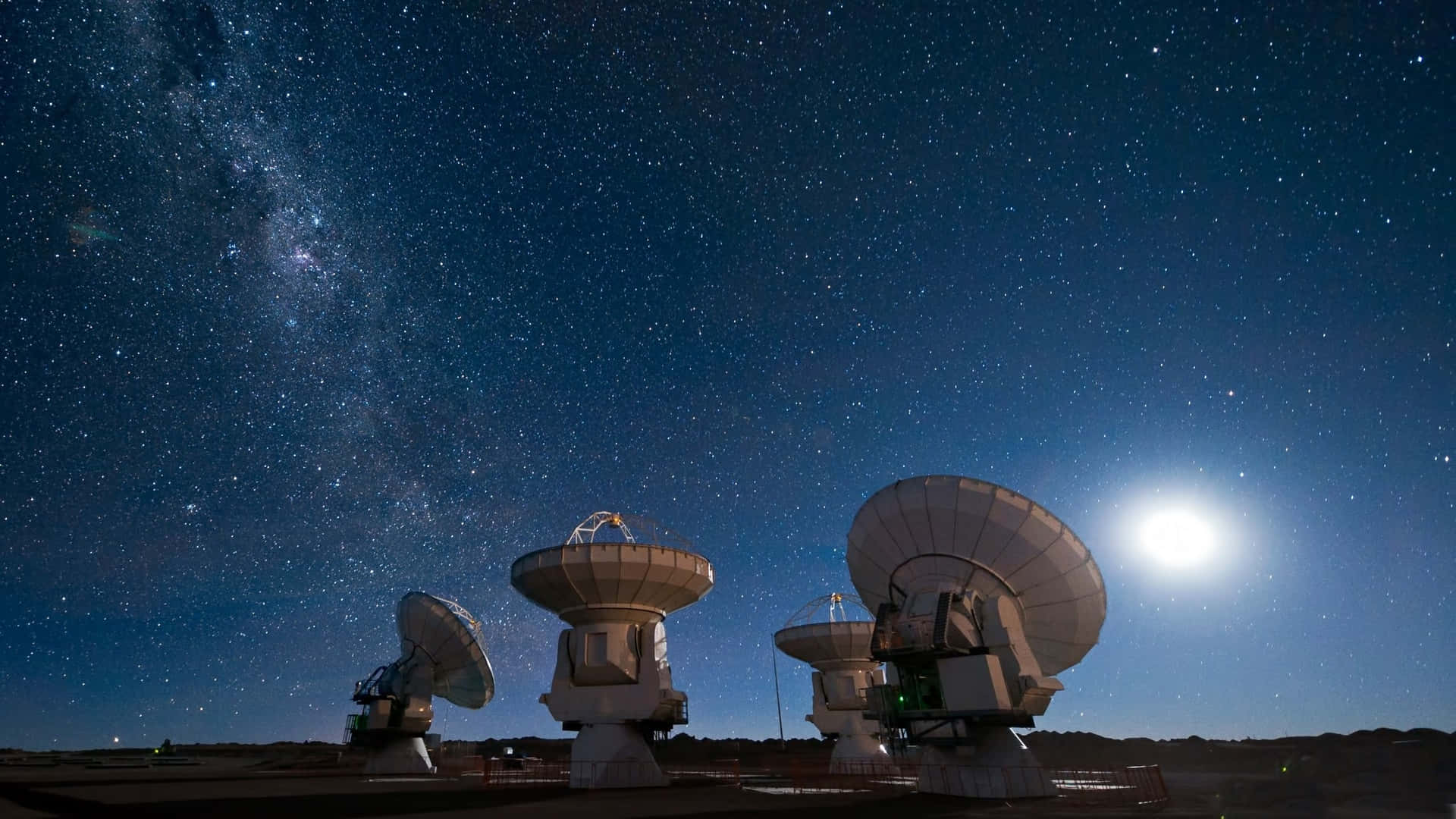 Satellite 桌布 壁紙 — 無線電望遠鏡矗立在繁星點點的夜空下，銀河和明亮的月亮在上方閃耀。